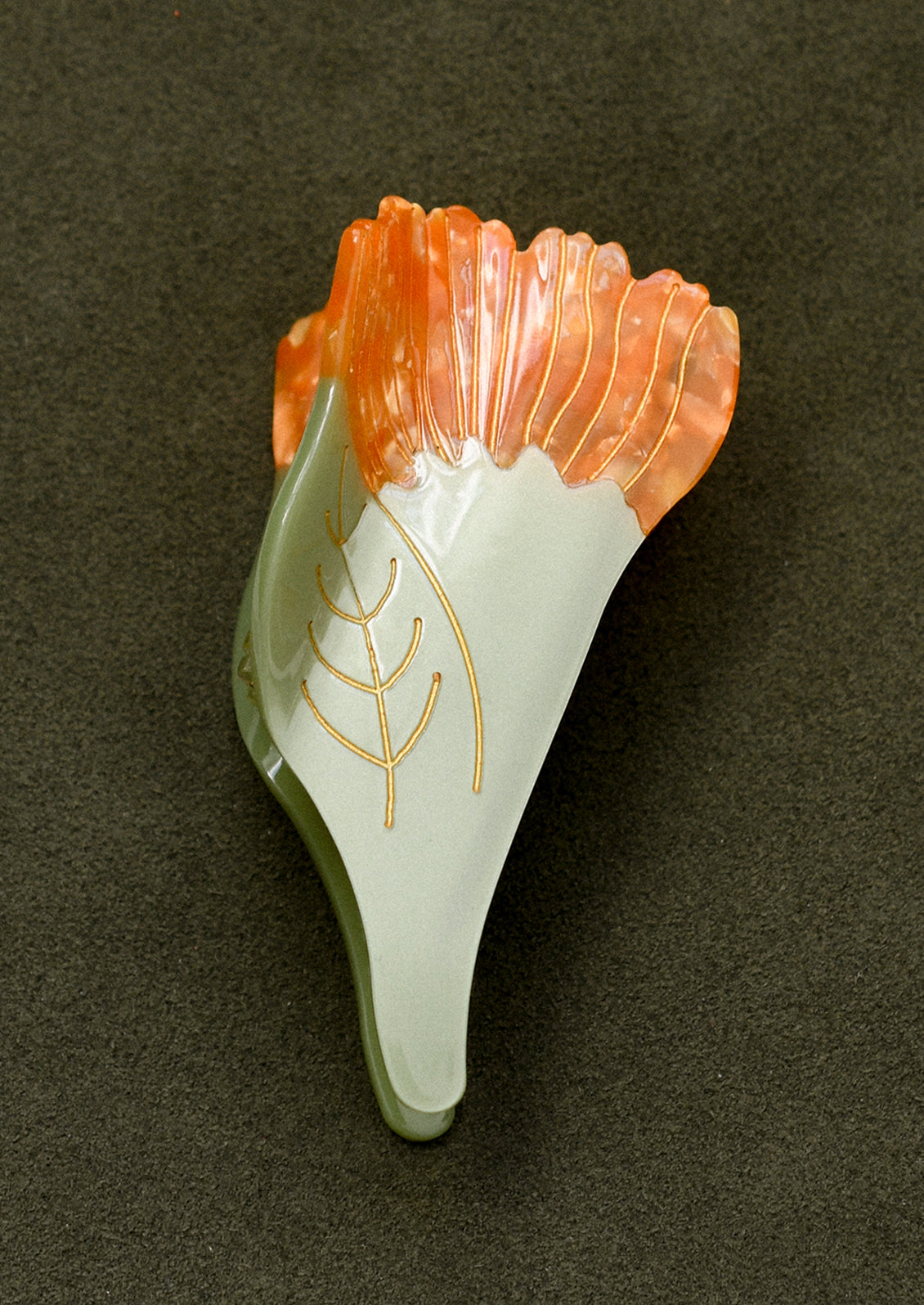 A green and orange hair claw in the shape of a marigold flower.