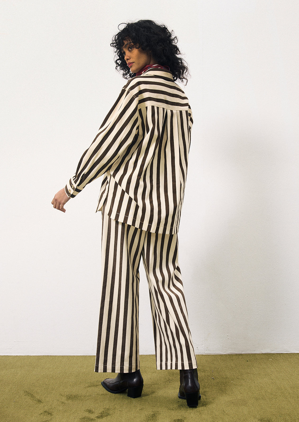 A woman wearing a cargo style button up shirt with vertical thick dark brown stripes on cream.