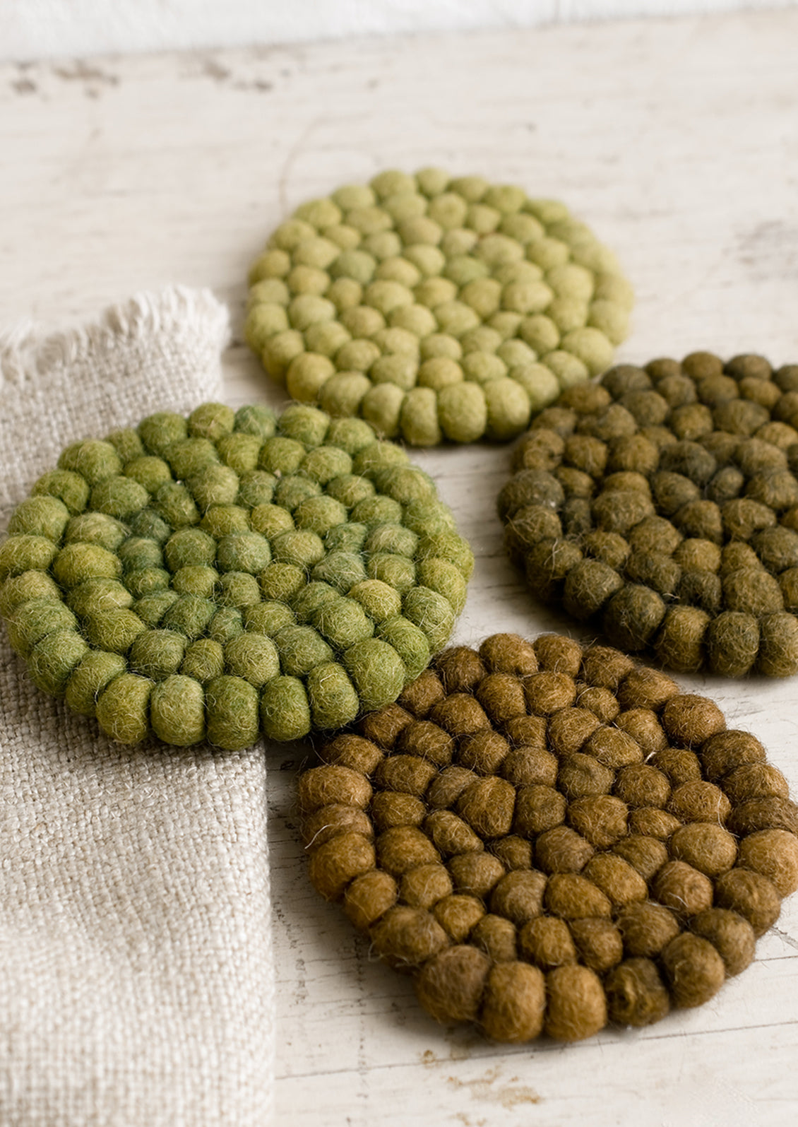 A set of felted ball coasters in mixed tones of green.