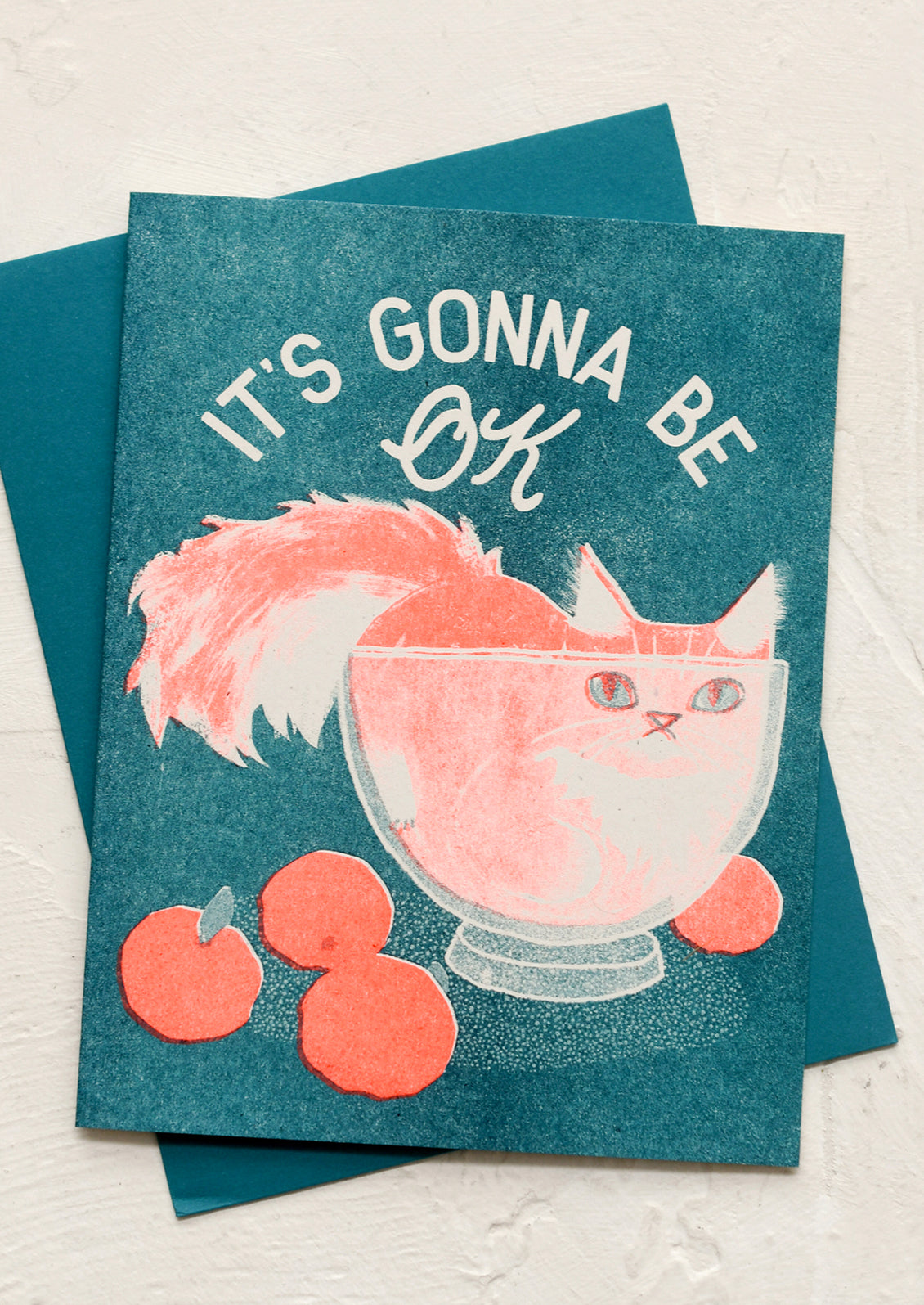 A risograph printed card with image of cat in bowl, text reads "it's gonna be ok".