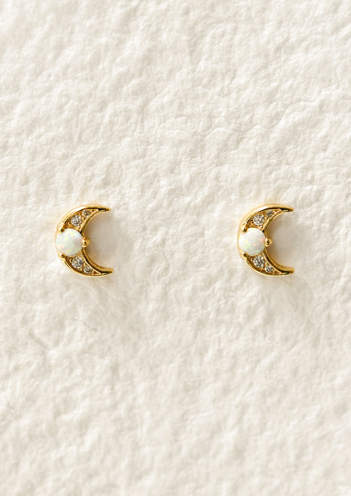A pair of gold moon-shaped earrings with opal gemstones.