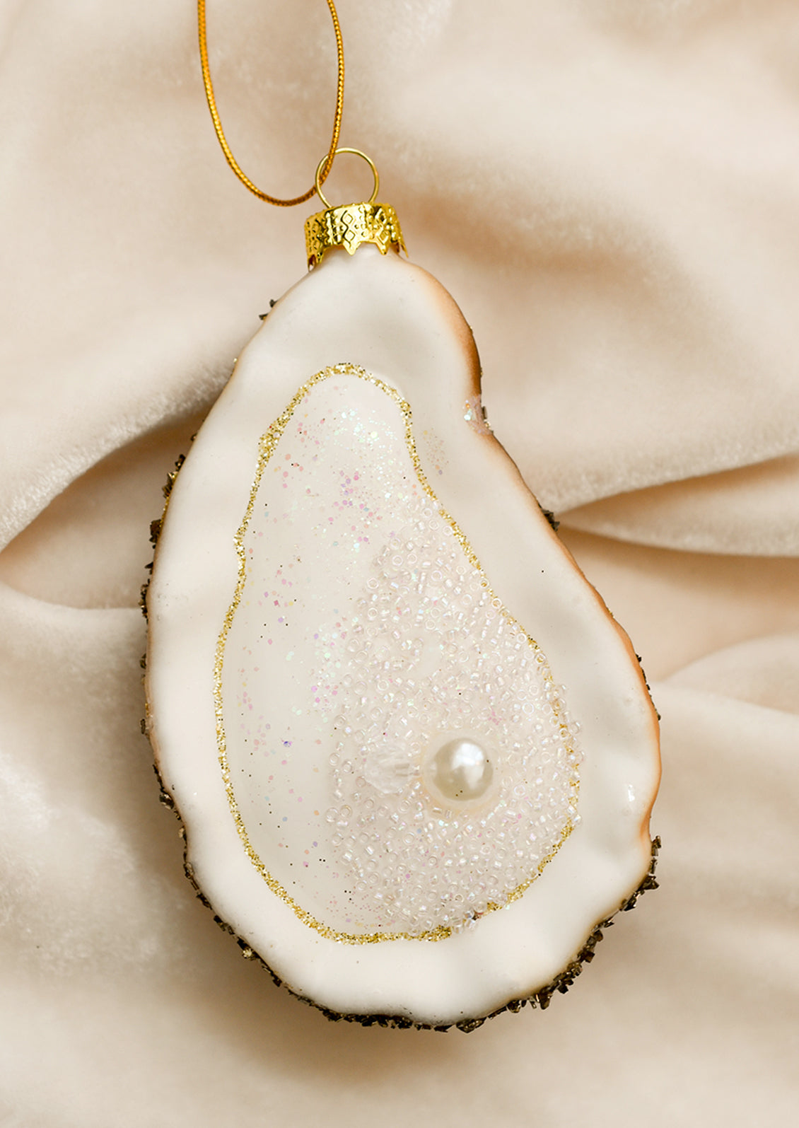 Glass oyster half shell ornament with pearl detail.
