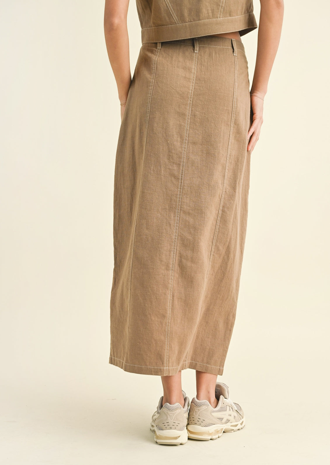 Woman wearing tan cotton midi skirt, seen from behind.