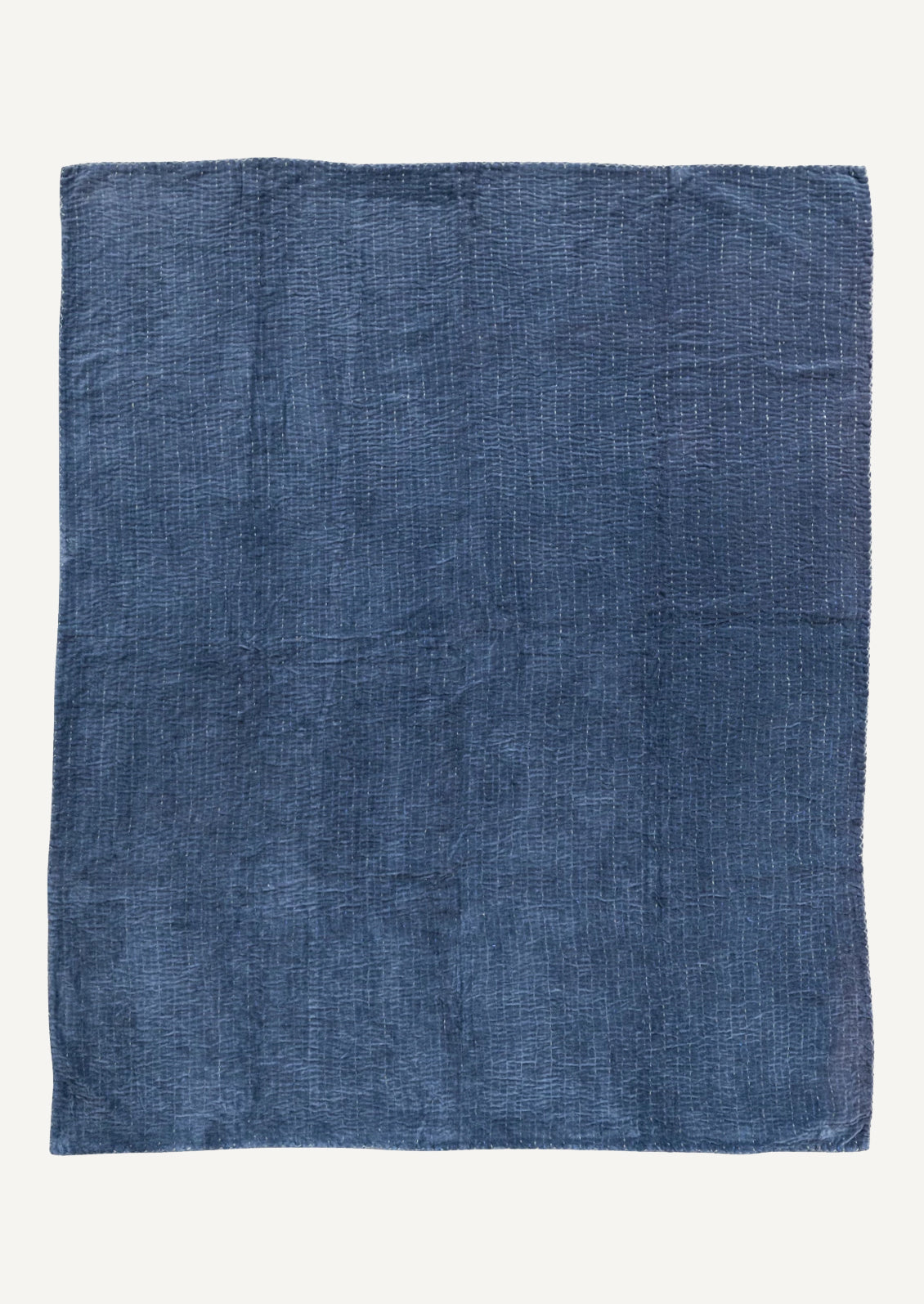 An indigo blue velvet throw blanket with blue and white kantha stitched stripes throughout.