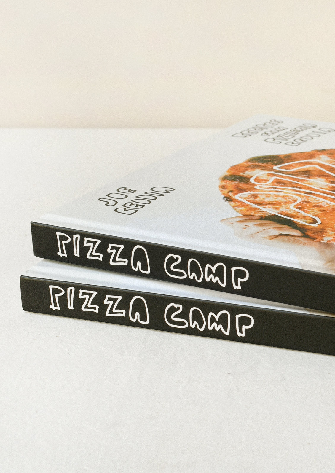 Two "Pizza Camp" book stacked on top of one another on a table.