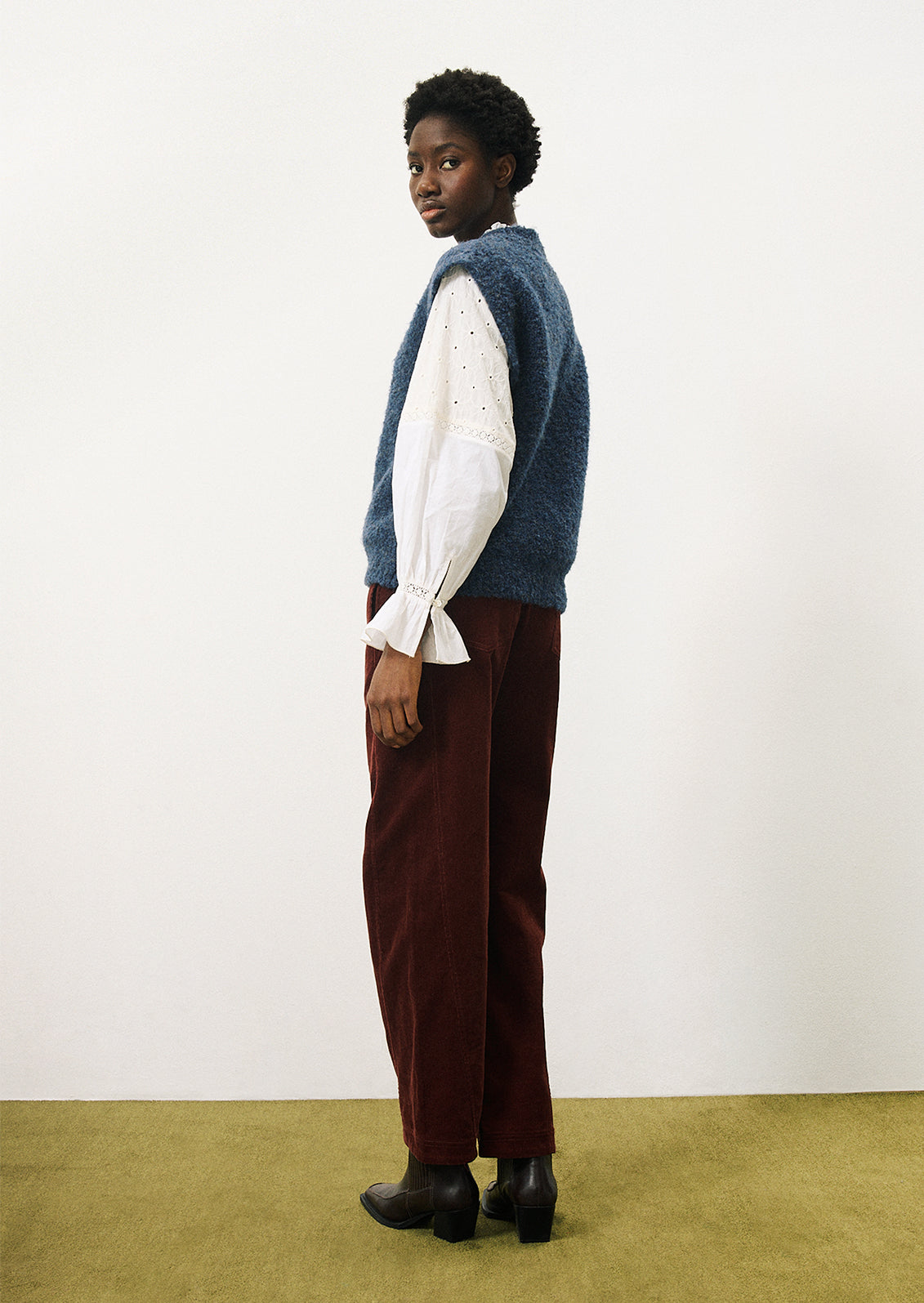 A woman wearing a cap sleeve sweater vest in marled blue knit with boucle texture.