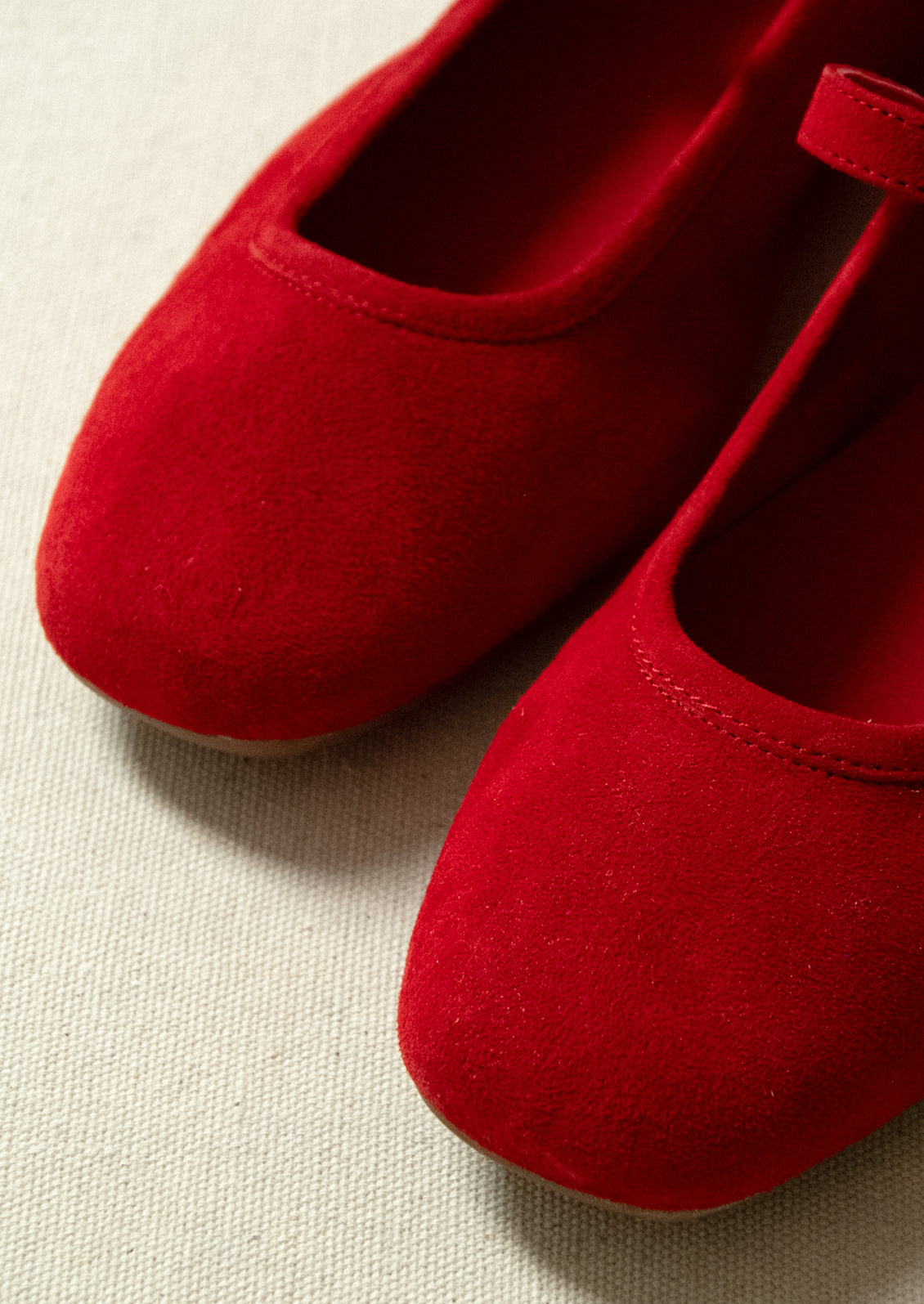 A pair of red suede mary jane flats.