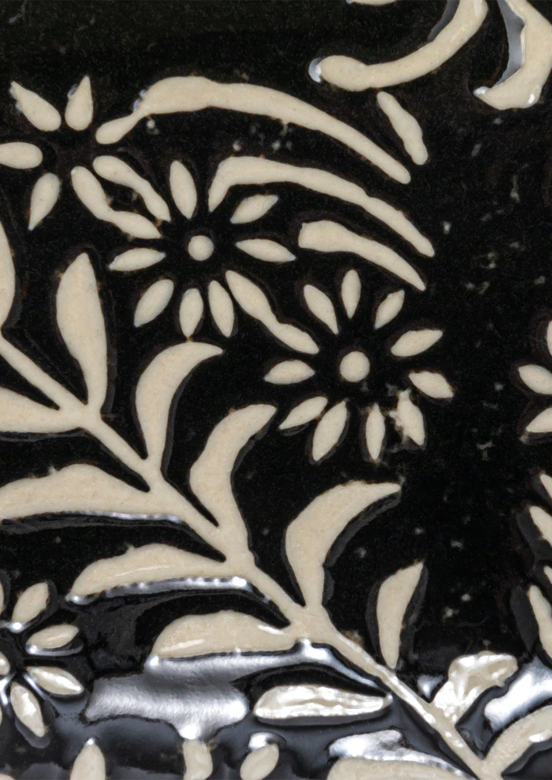 A slim, oval shaped ceramic tray in black with white botanical pattern.
