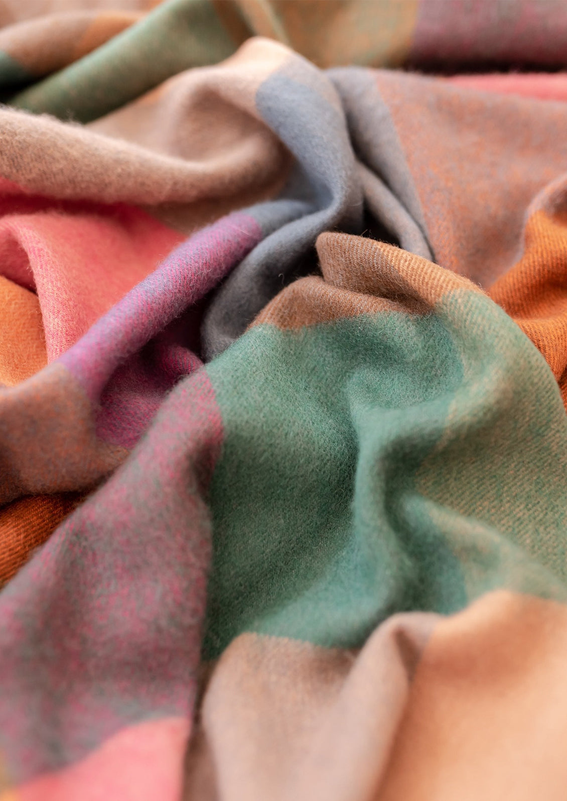 A madras check print wool throw in shades of peach, pink, teal, orange and blue.