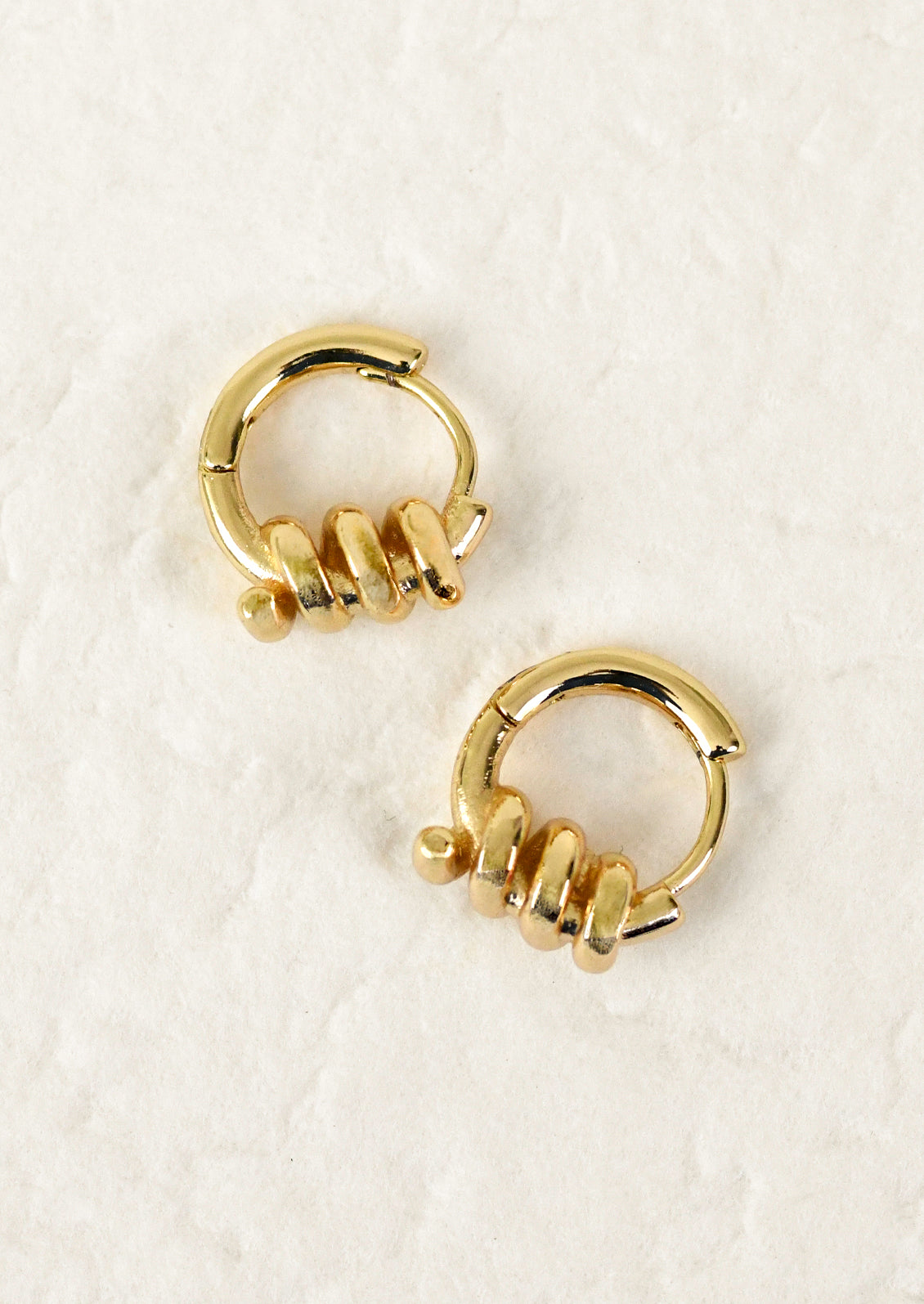 Gold hoop earrings on a textured white surface