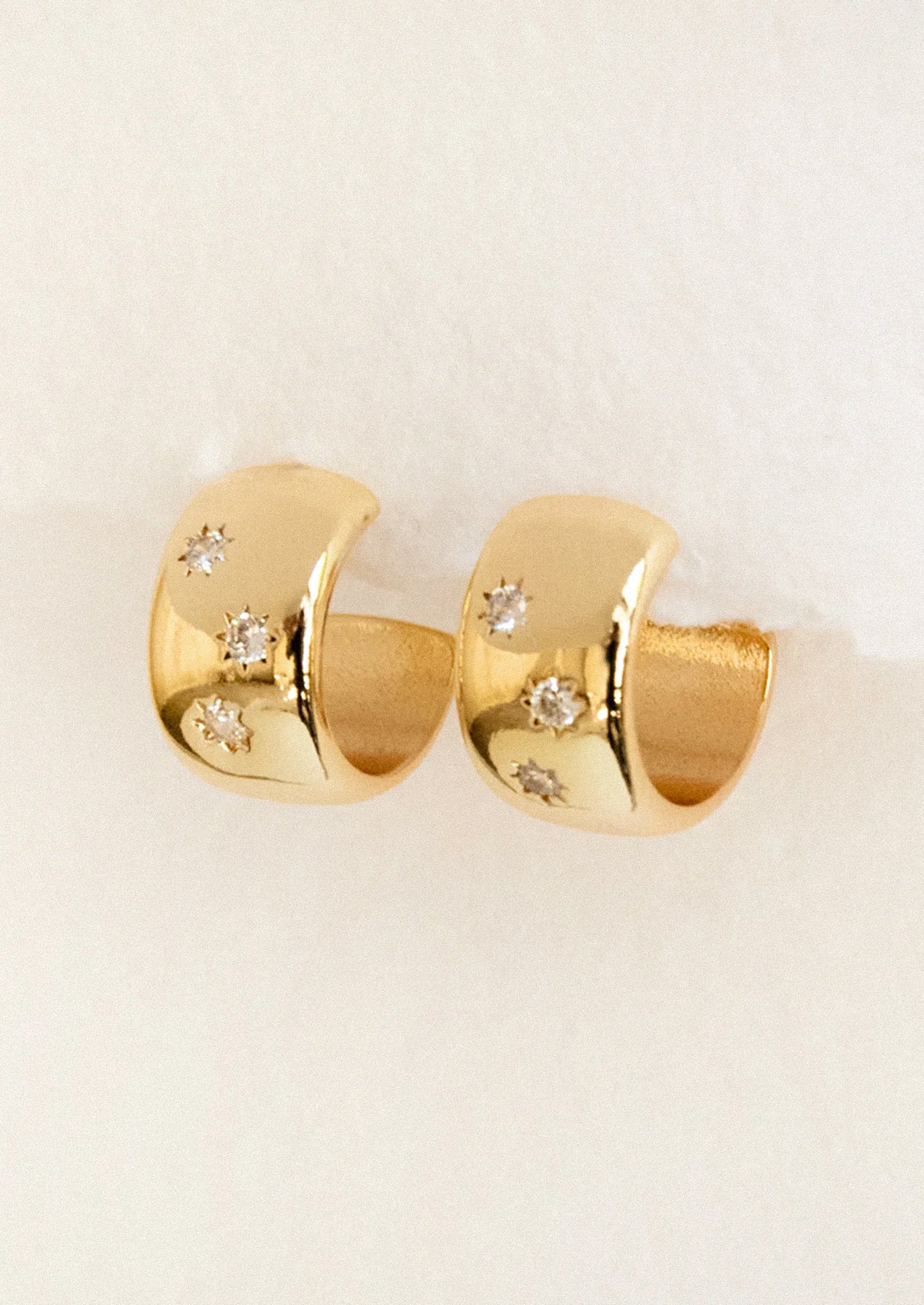 A pair of chunky gold hoops with starry gems.