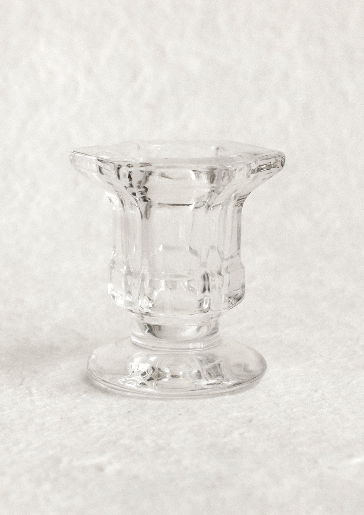 A footed glass candleholder in clear glass.