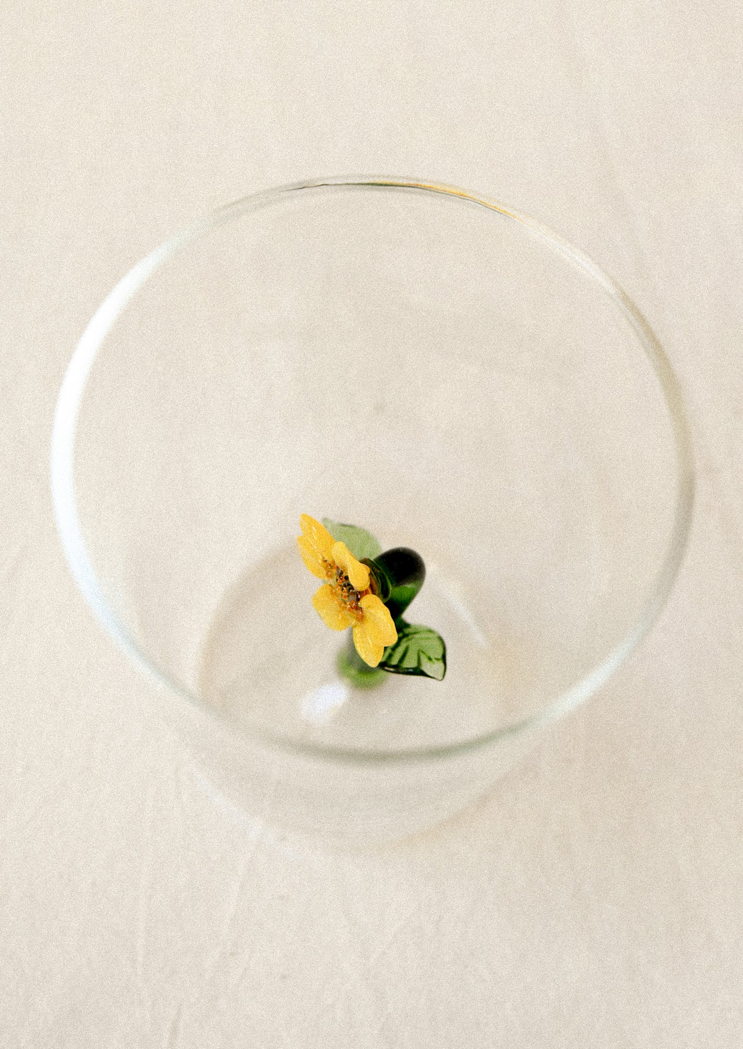 Clear drinking glass with a yellow sunflower charm inside glass.