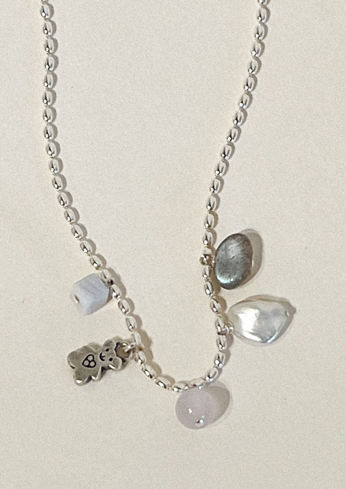 A sterling silver necklace with a teddy bear charm and other various gems.