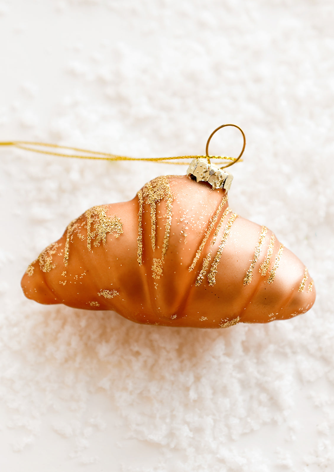 A glass ornament of a plain croissant.