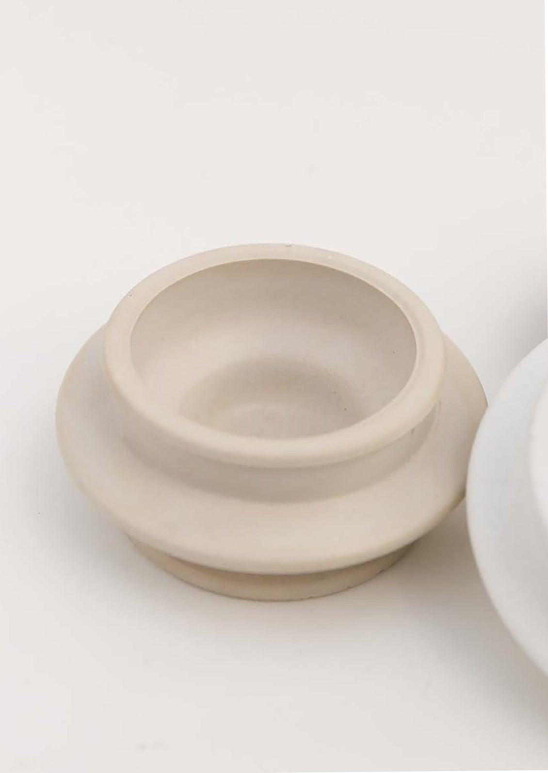 An architecturally shaped tealight holder in sand.