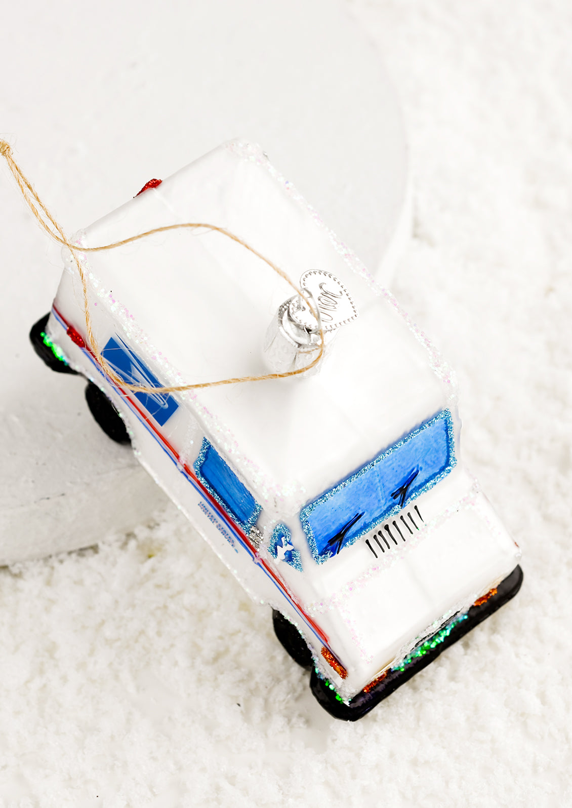A glass holiday ornament that looks like a USPS mail truck.