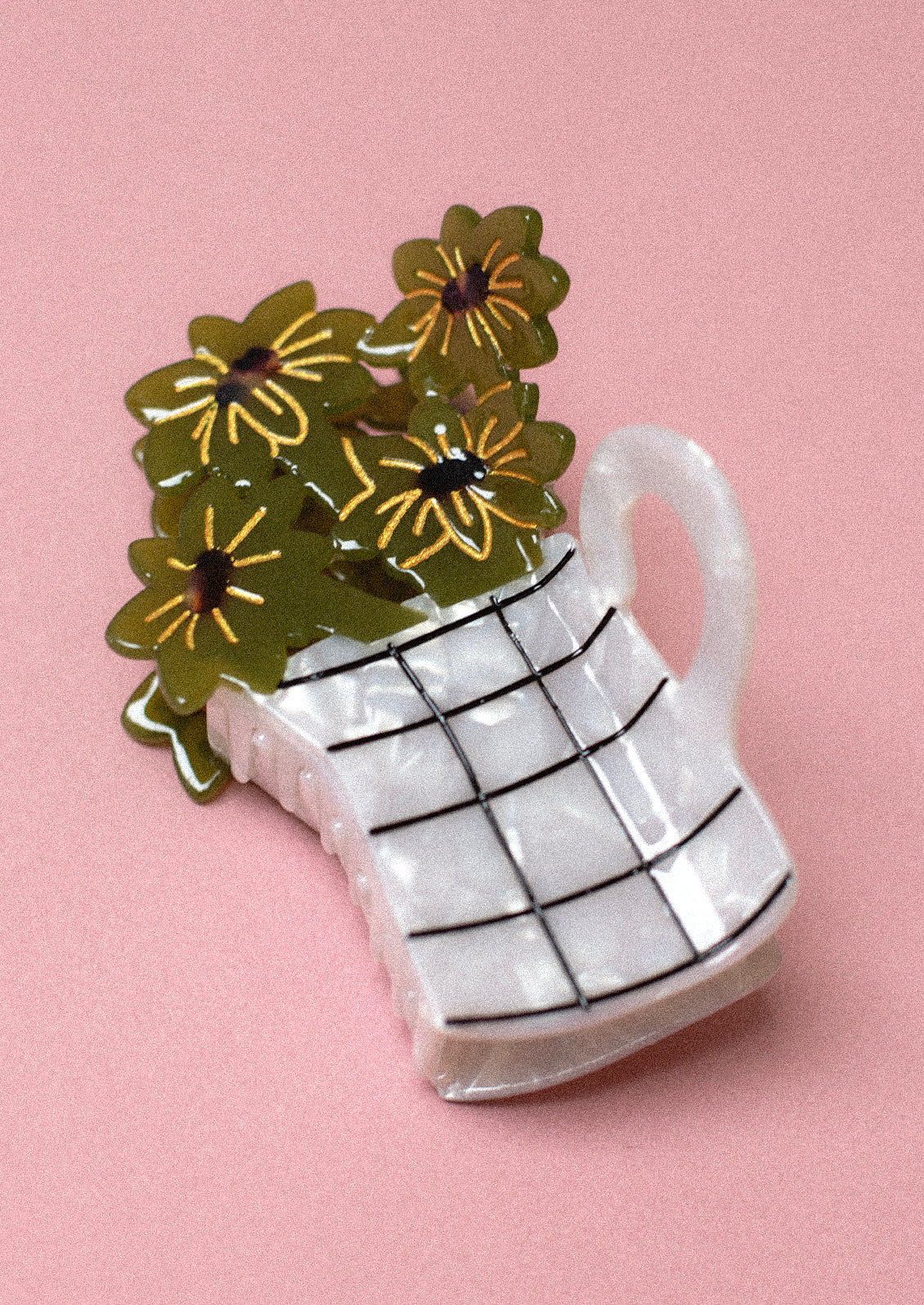 A hair claw depicting white pitcher holding green flowers.