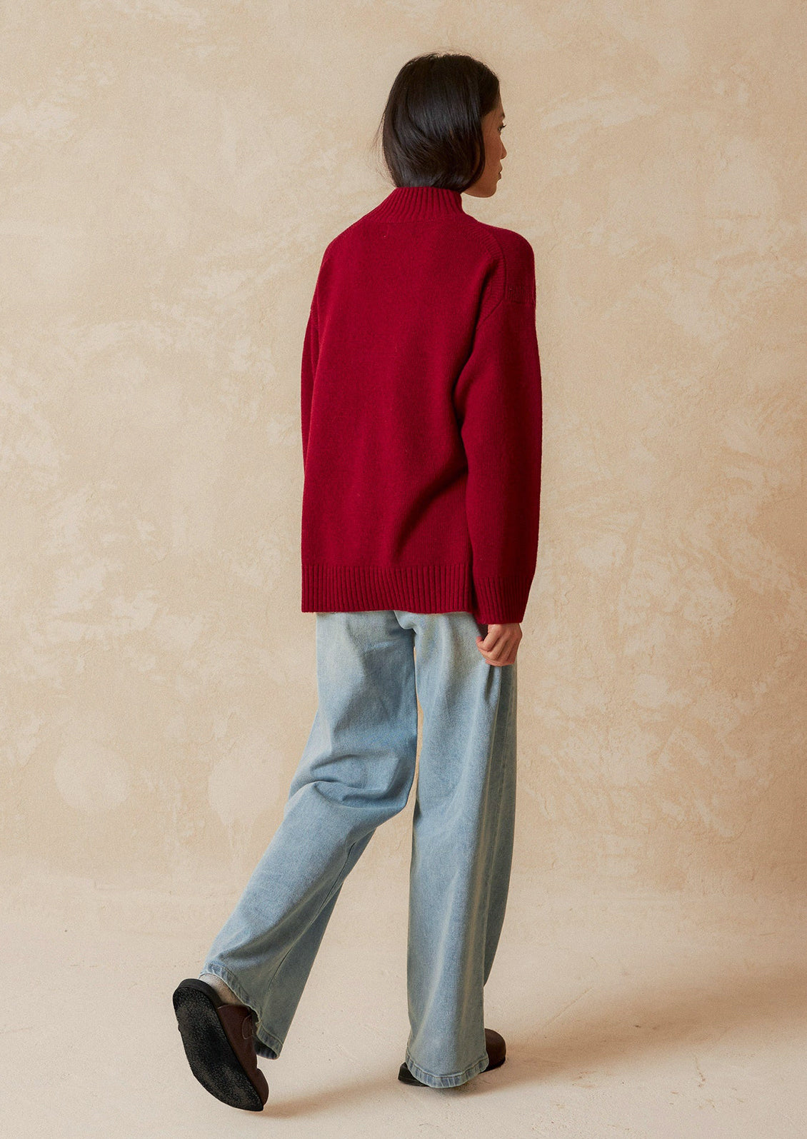 A woman wearing an oversized mockneck sweater.