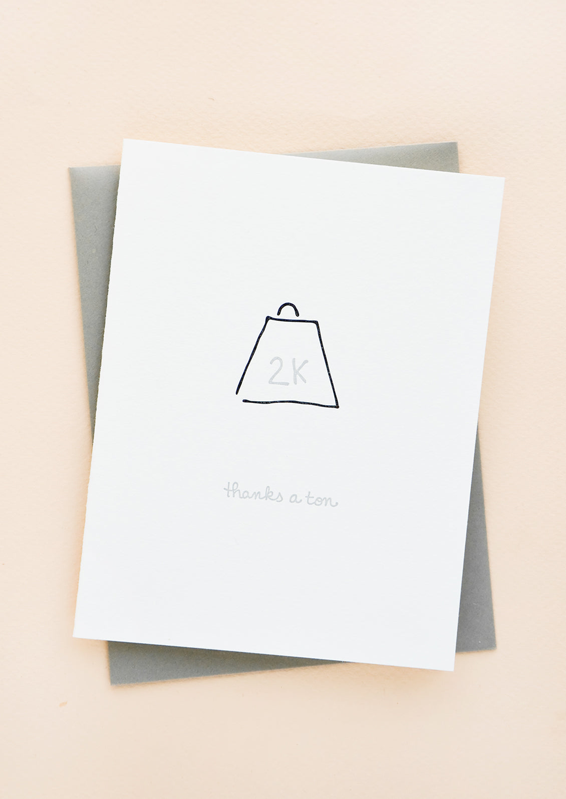 Greeting card with letterpress 2k weight and cursive text reads "Thanks a ton", with gray envelope