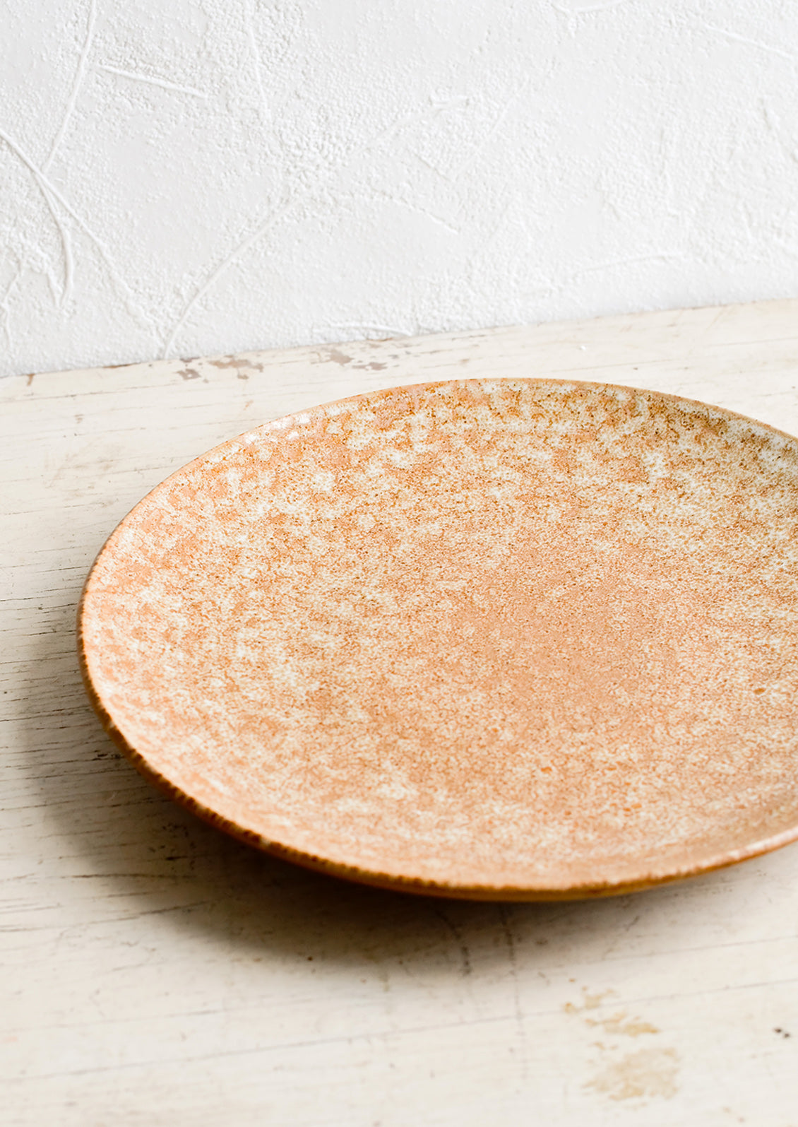 A round ceramic plate in dappled, glossy light brown glaze.