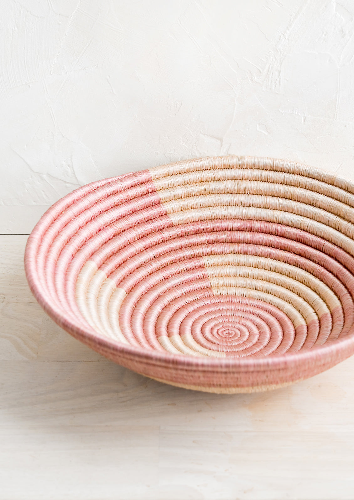 A woven sweetgrass bowl in geometric pink pattern.