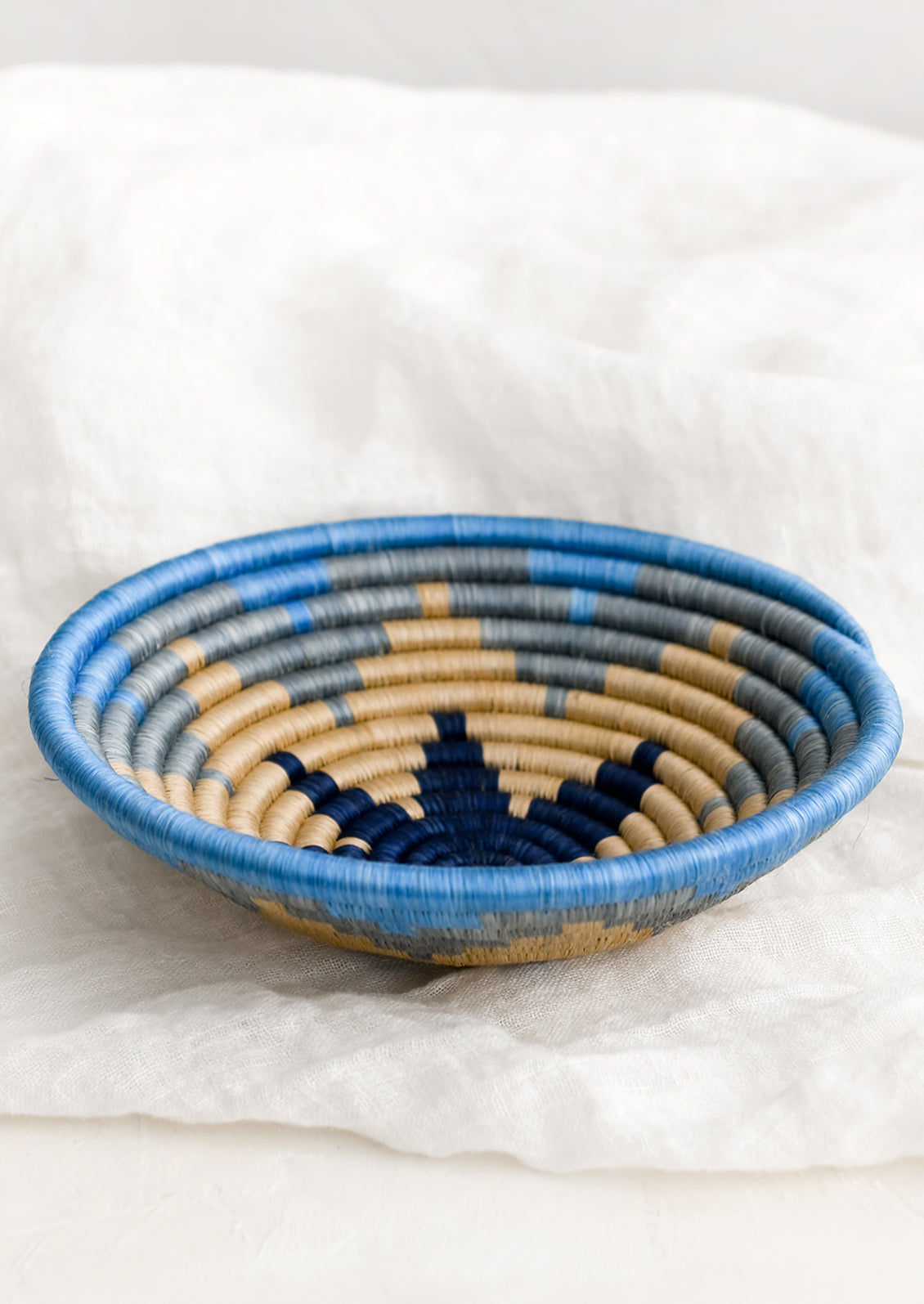 A blue and tan woven sweetgrass catchall with star pattern.