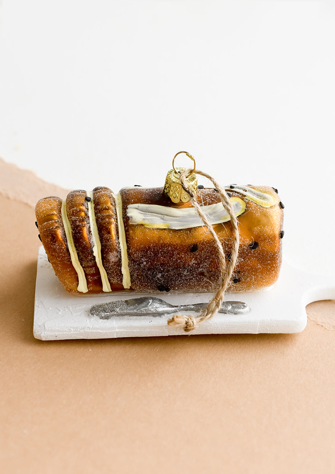 A decorative holiday ornament in shape of loaf of banana bread on platter.