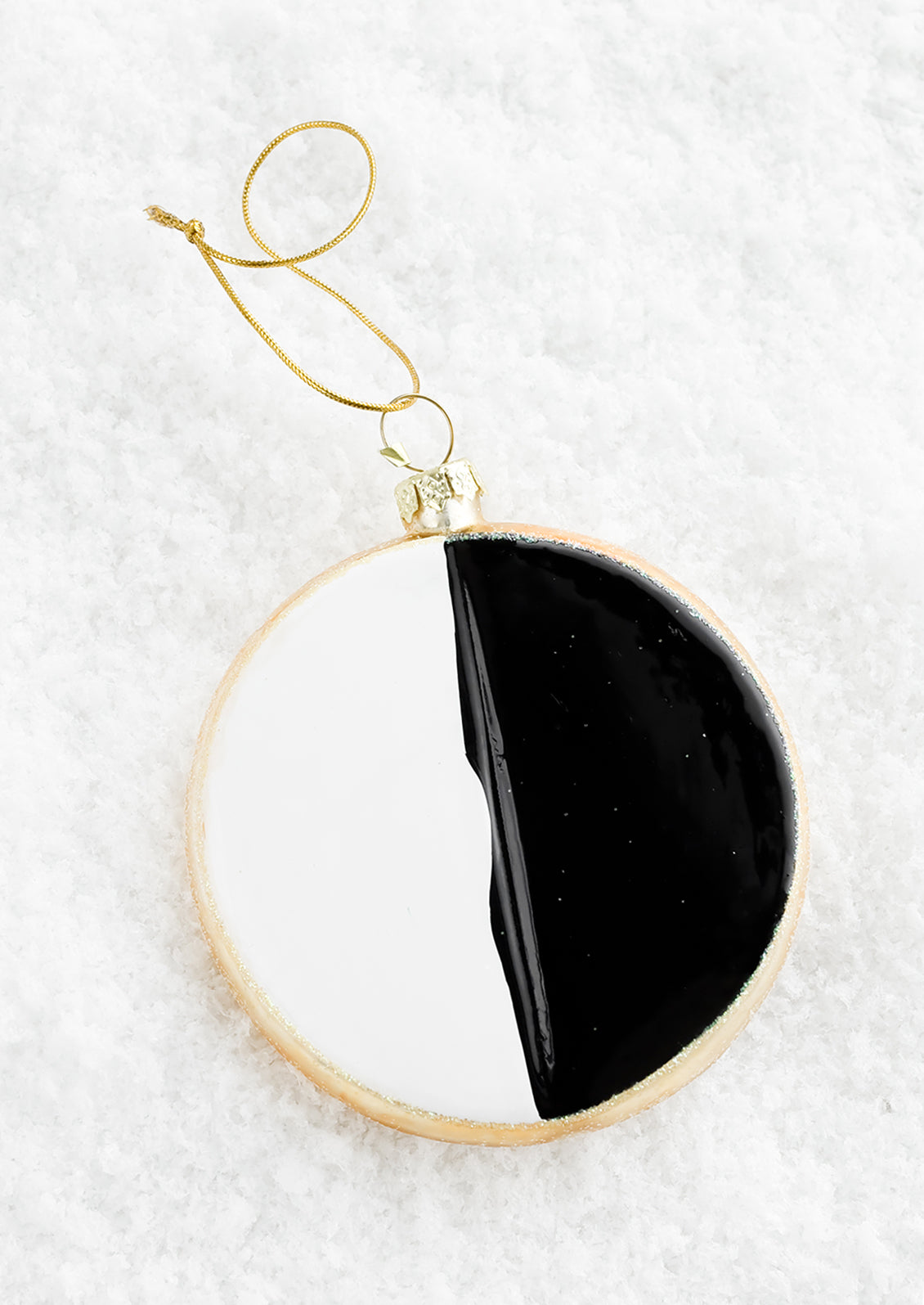 A decorative holiday ornament in the shape of a black & white cookie.