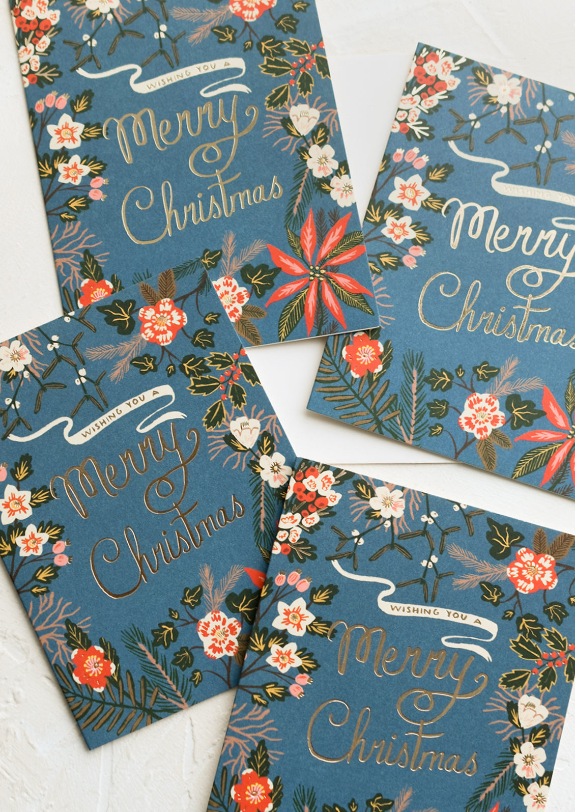 Blue greeting cards with poinsettia floral print, gold text reads "Wishing you a merry christmas".