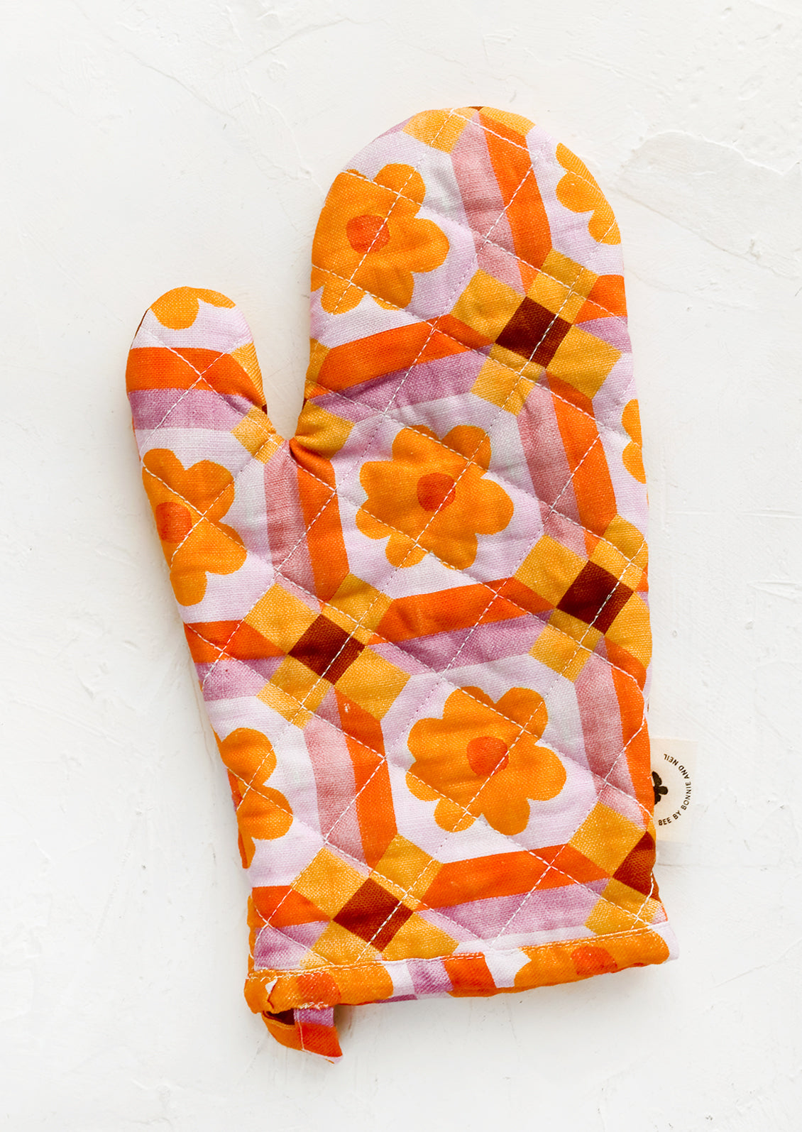 An oven mitt with retro floral pattern in pink and orange.