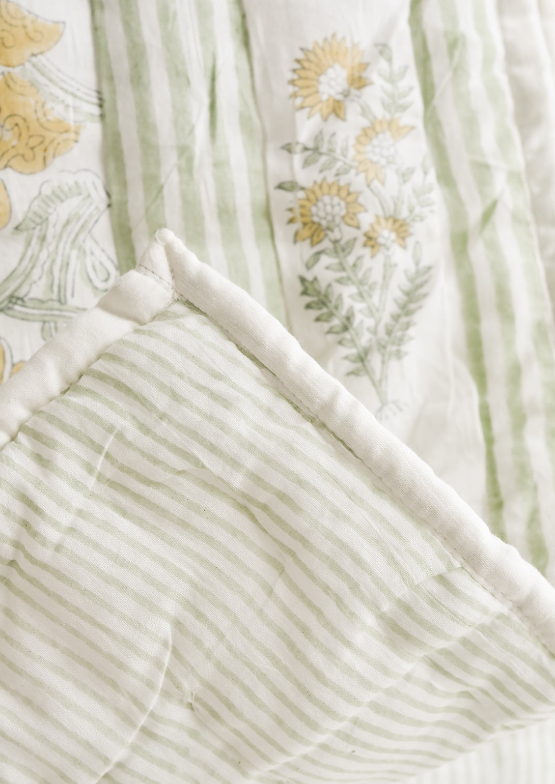 A quilt with botanical print on one side and stripe on back.