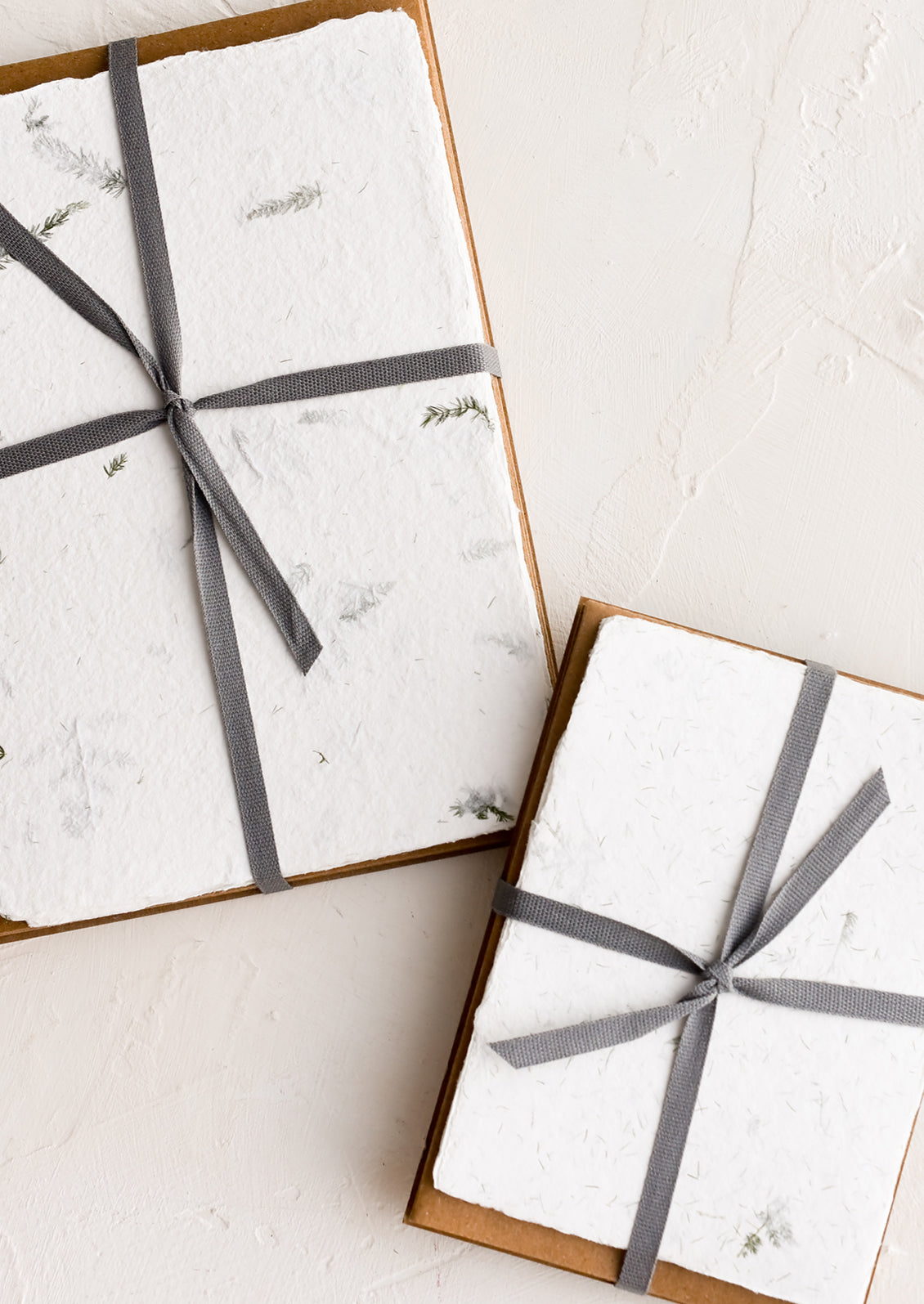 Handmade fern leaf paper and kraft envelopes bound with grey ribbon.