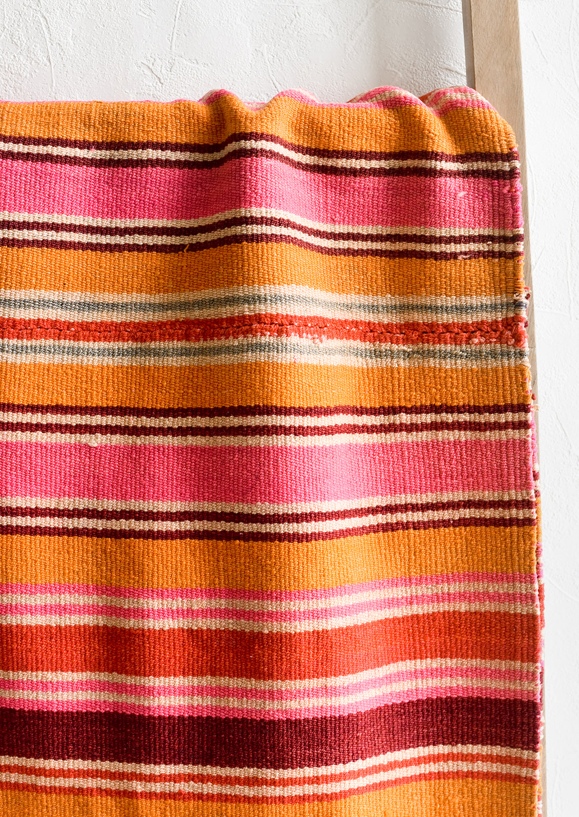 A vintage textile in thin pink, orange and burgundy stripe.