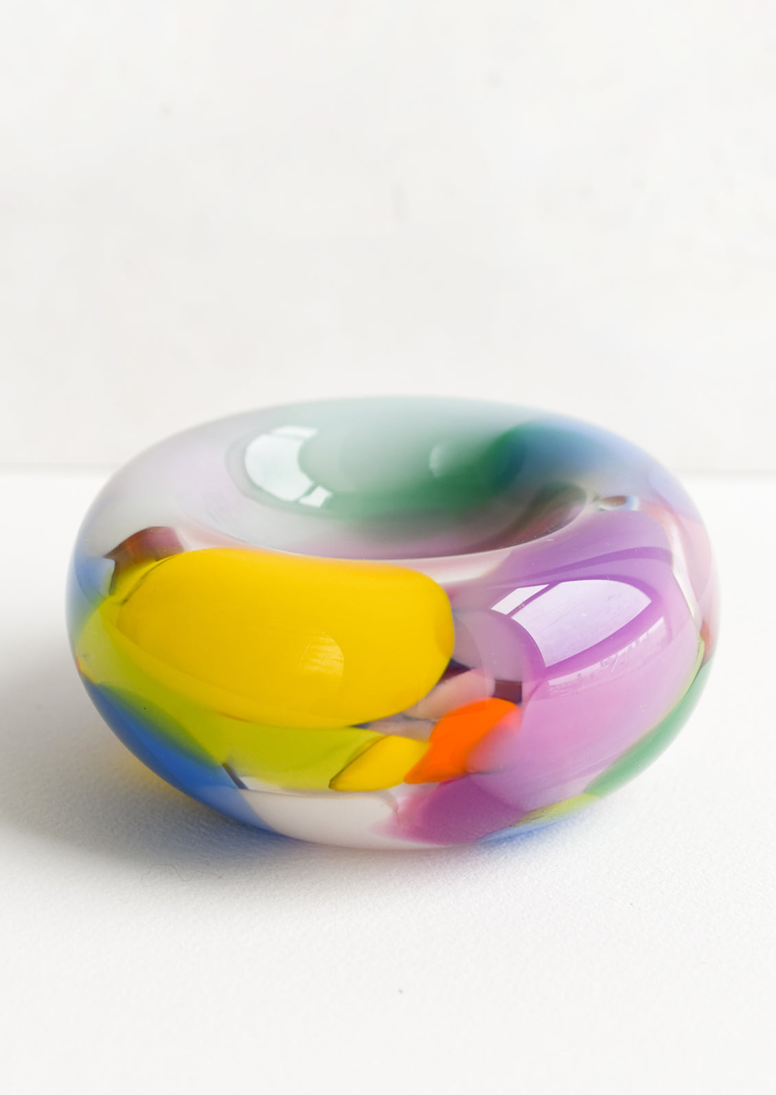 A multicolor, rainbow-hued hand-blown glass catchall bowl.