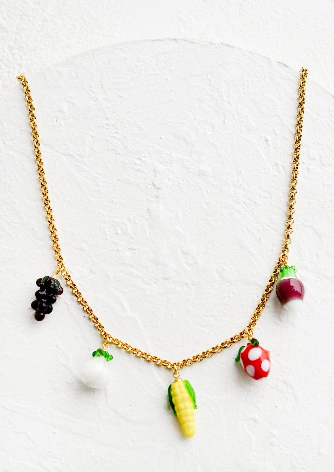 A gold chain necklace with glass fruit and veggie charms.