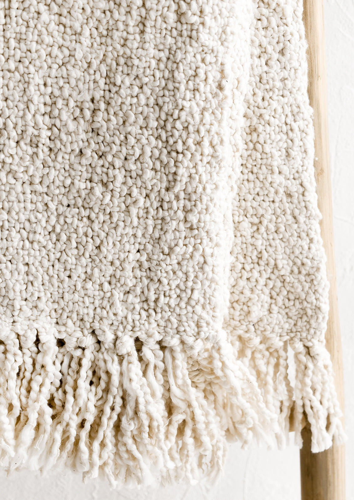 An ivory colored cotton throw with chunky boucle texture.