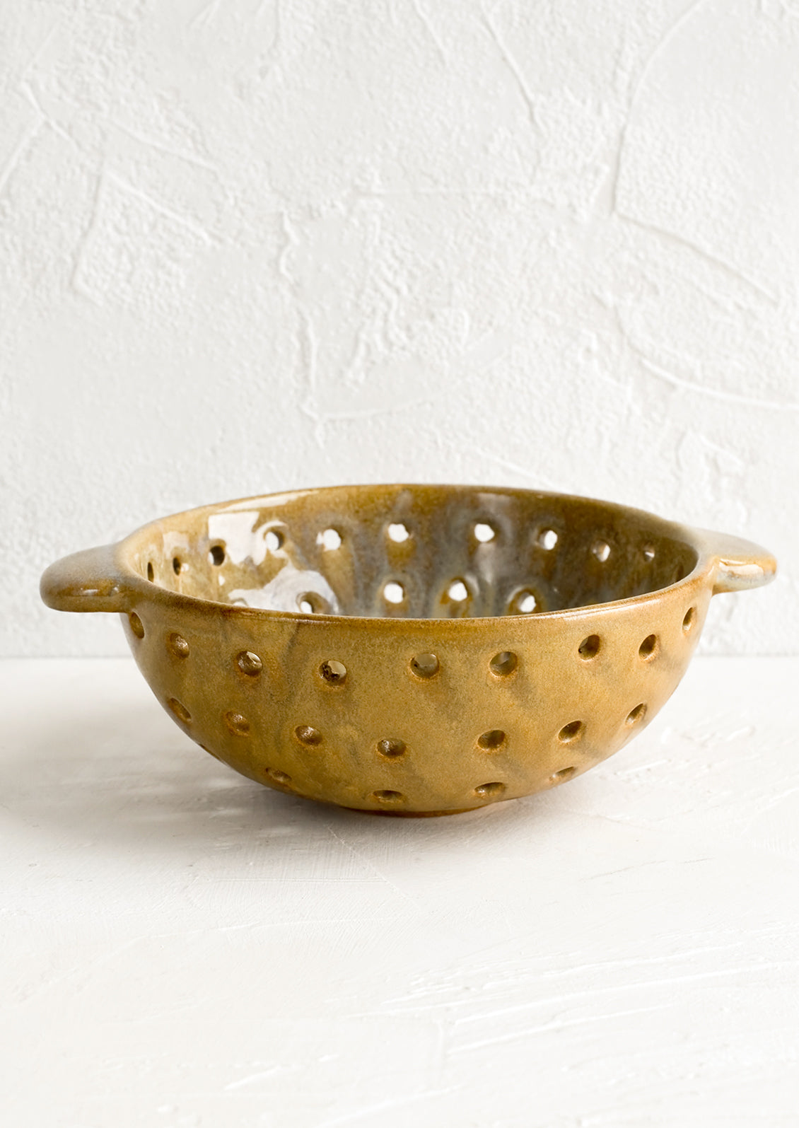 A round brown ceramic berry colander bowl.