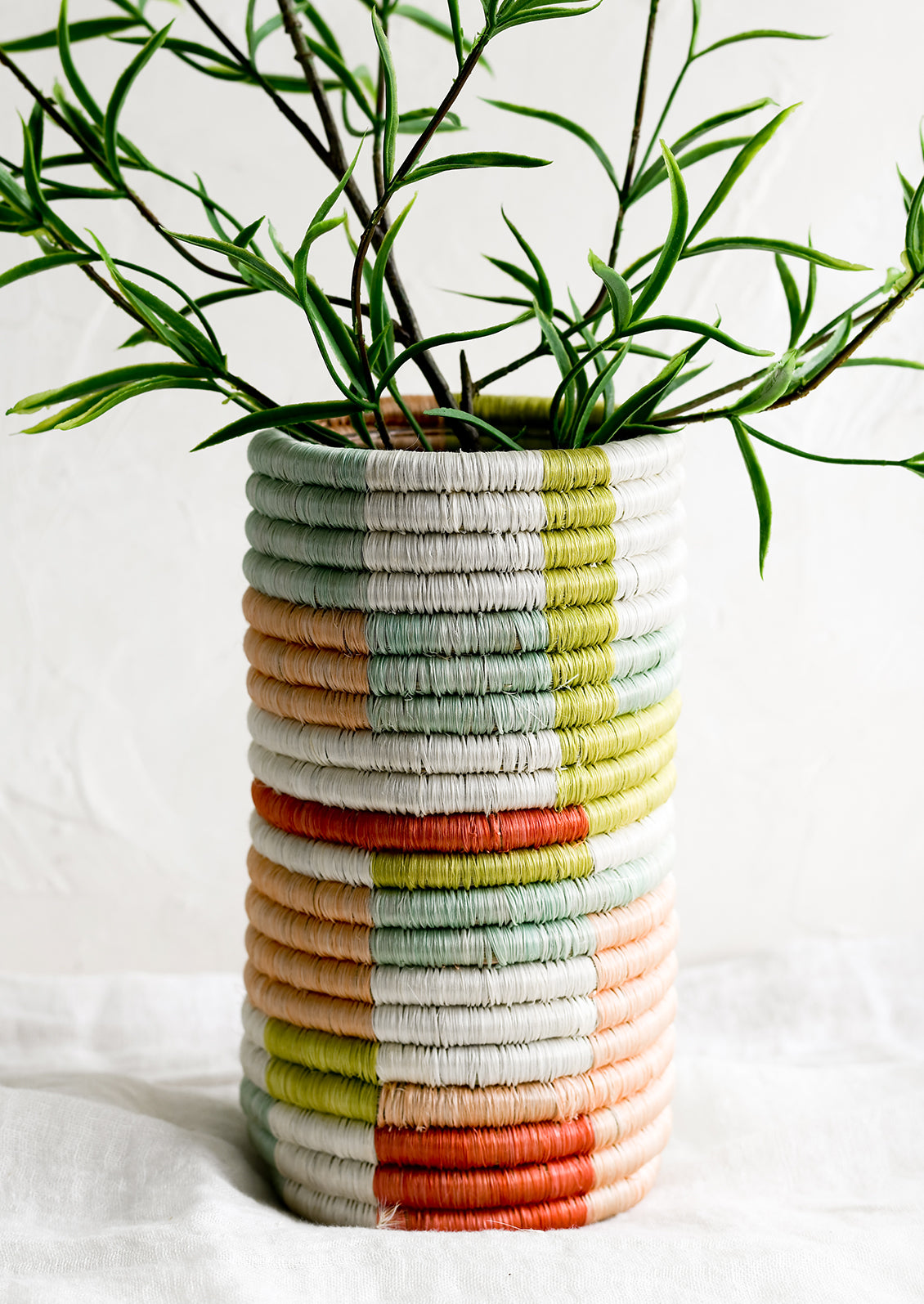 A woven sweetgrass vase with multicolor geometric pattern.