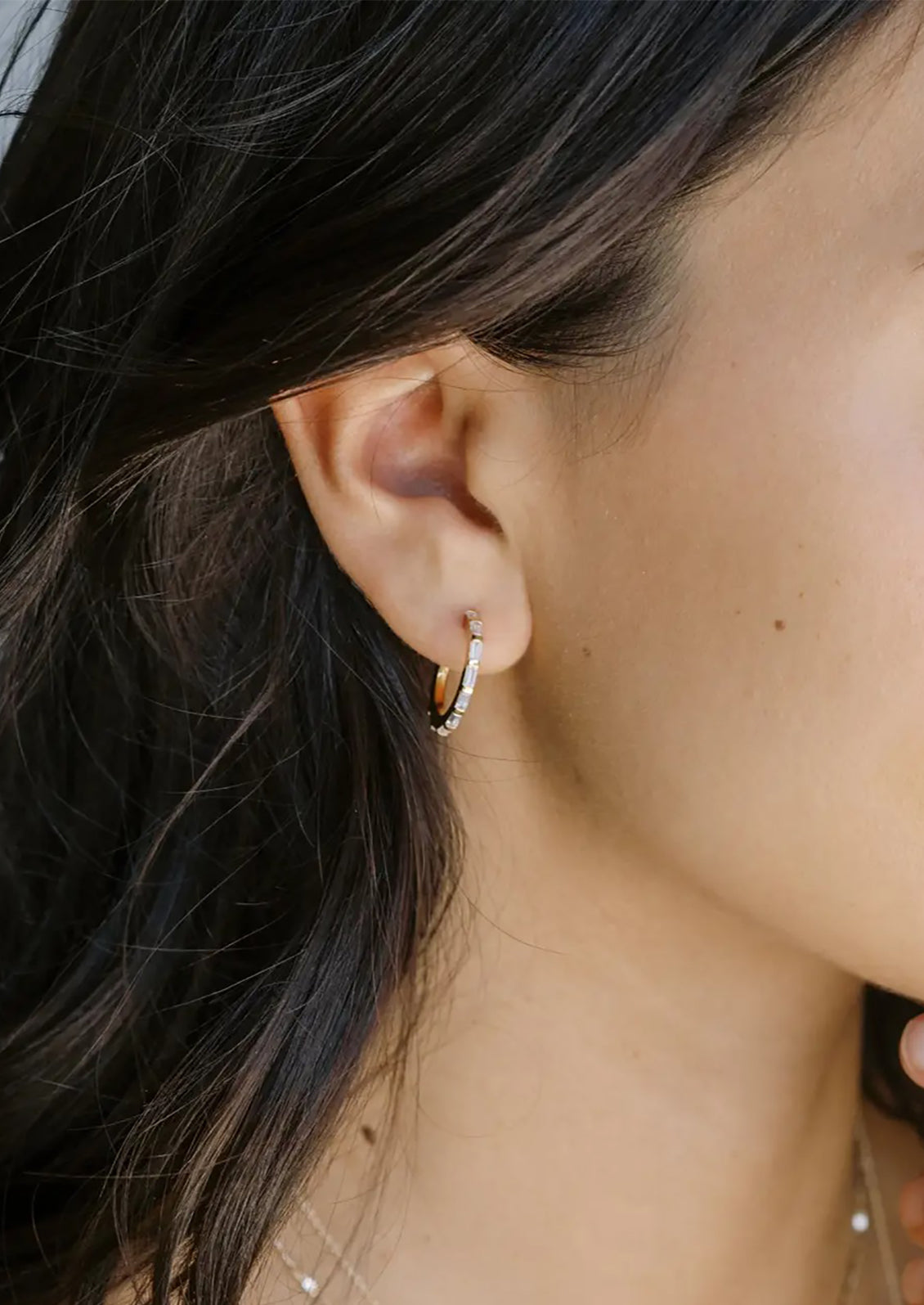 A pair of gold hoops with clear baguette shape crystals.