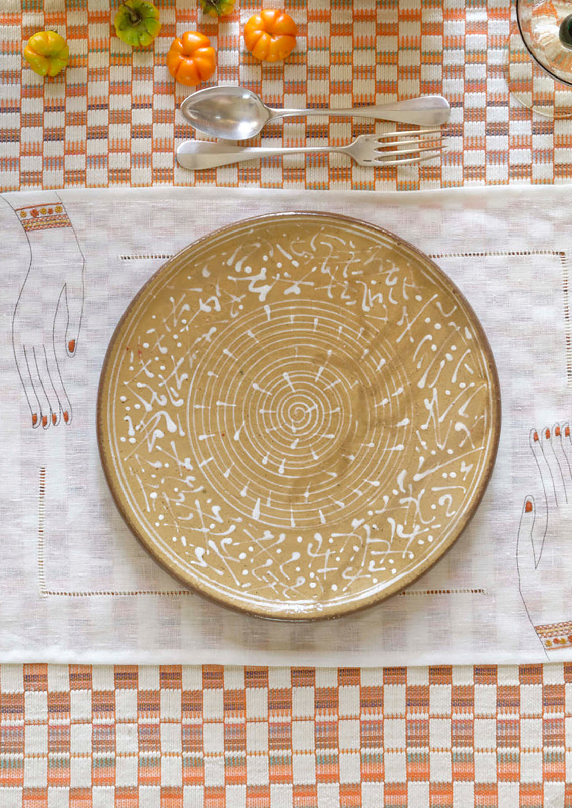 A table setting with placemat, plate and tablecloth.