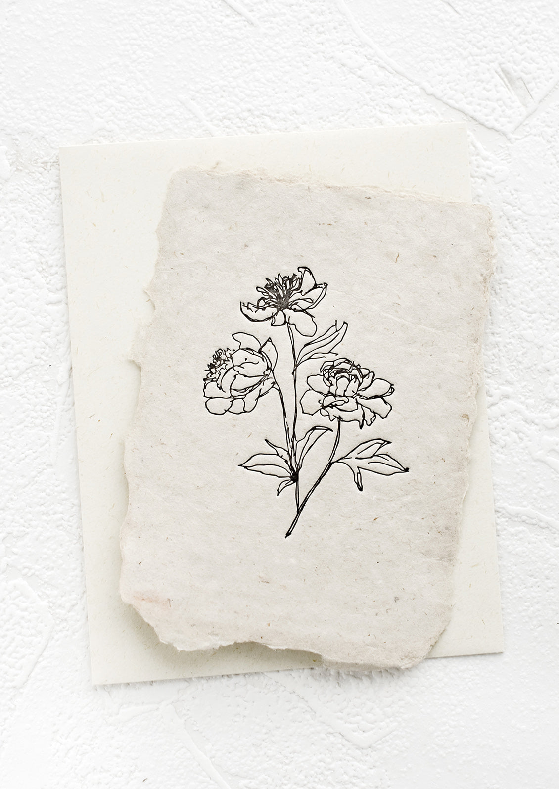 A greeting card made from handmade paper with a letterpress printed image of peony stems.