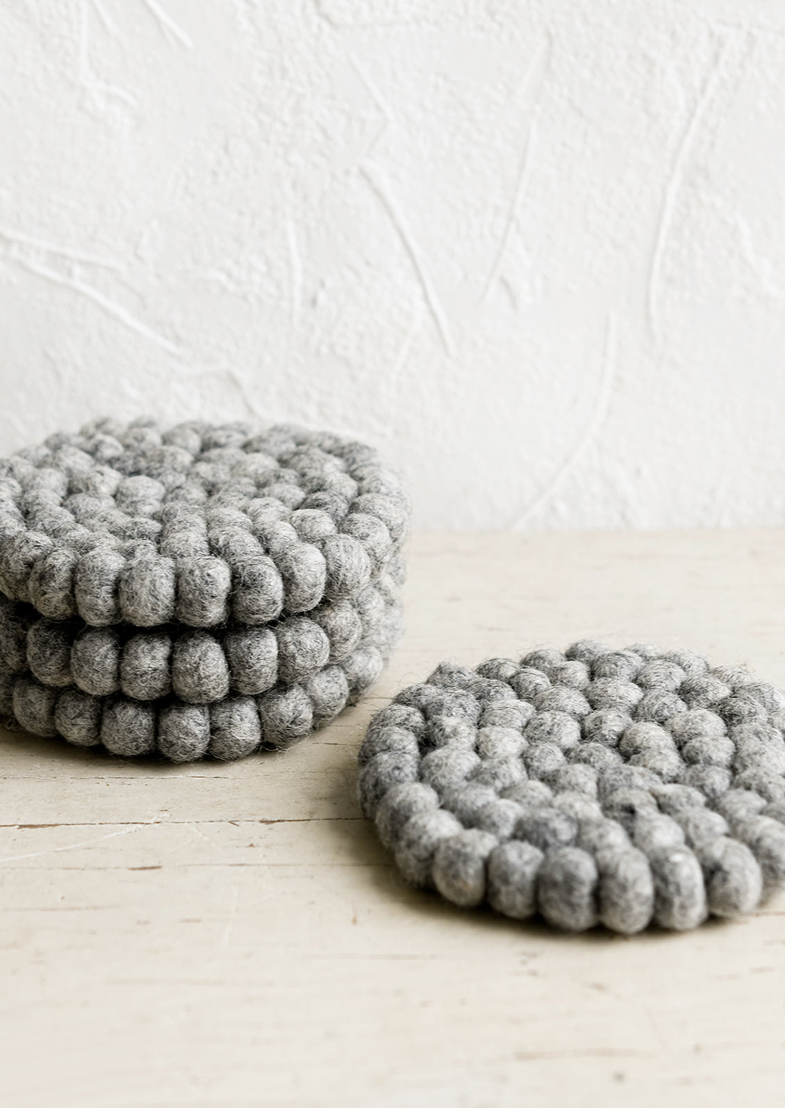 A set of round felted wool coasters in heather grey.