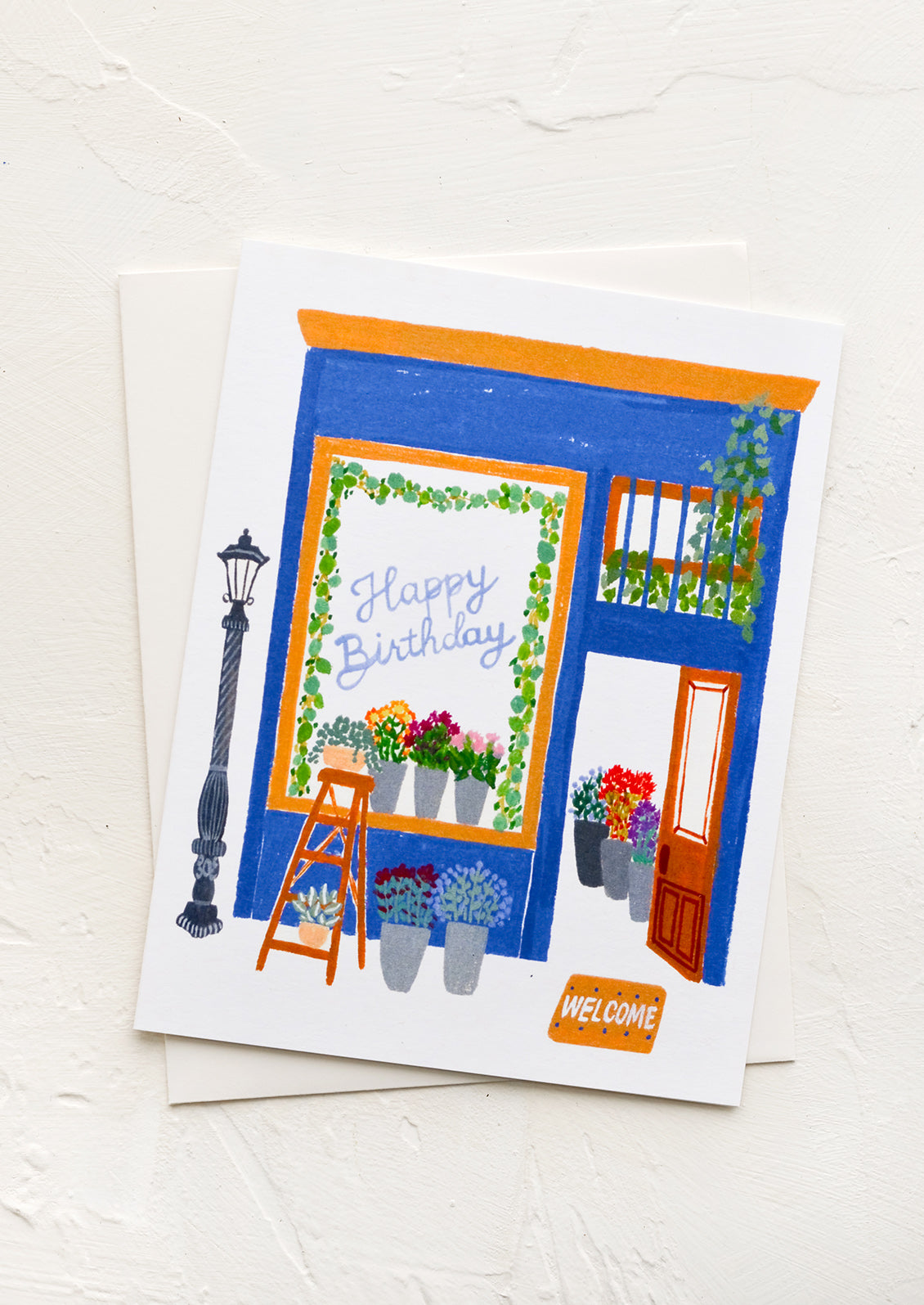 A greeting card with image of flower shop with "Happy birthday" written in window.