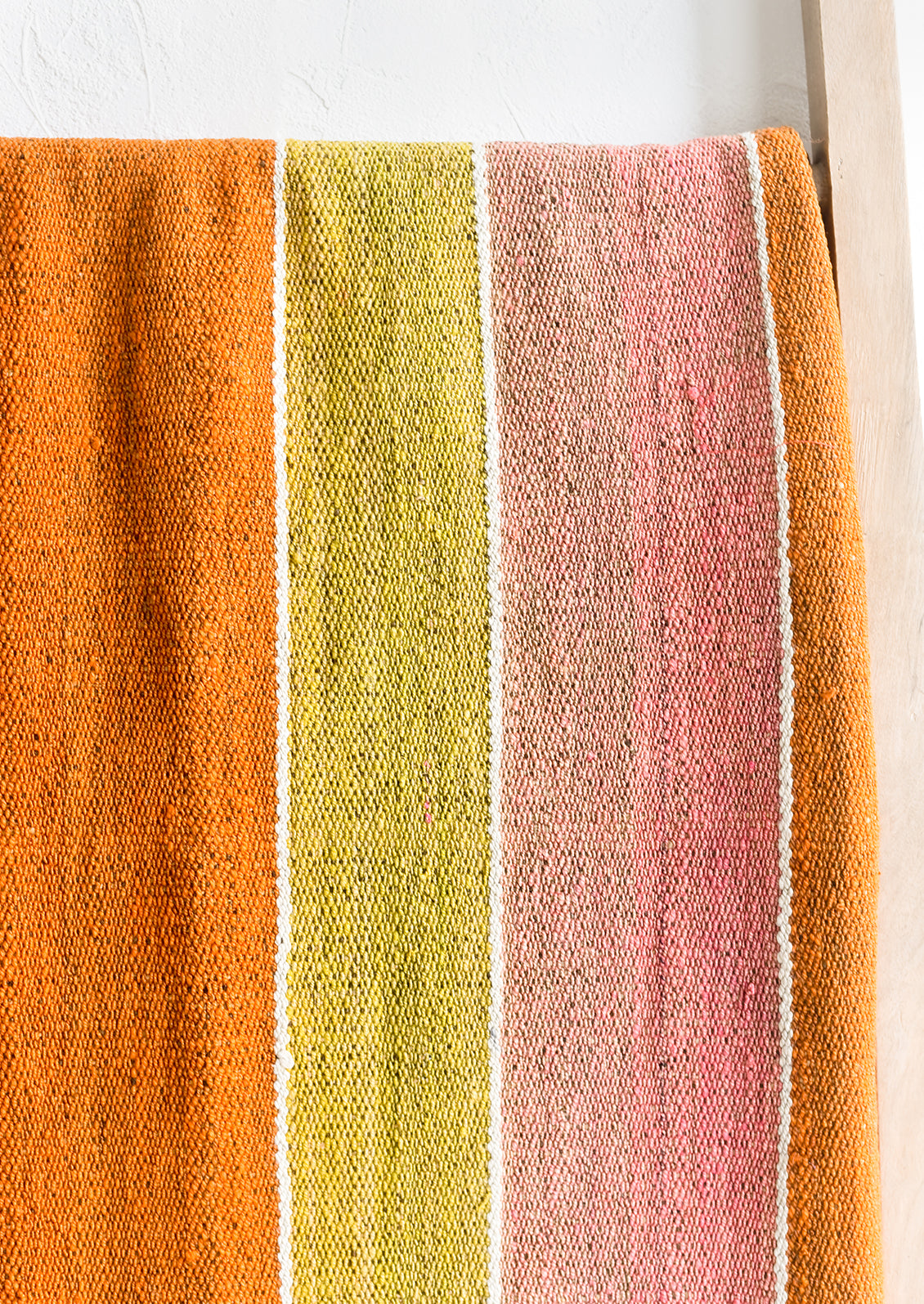 A vintage frazada textile in wide stripe pattern in orange, pink and yellow.