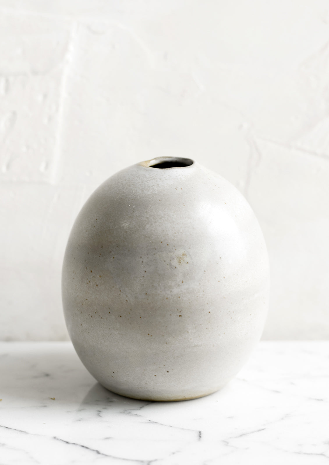 A round bud vase in grey ceramic with soft speckles.