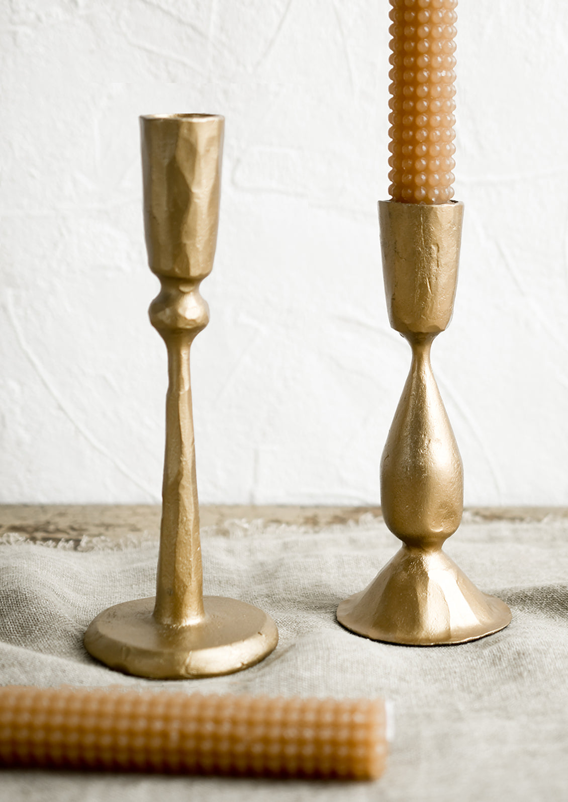 Golden metal candlestick holders with hobtail taper candles.