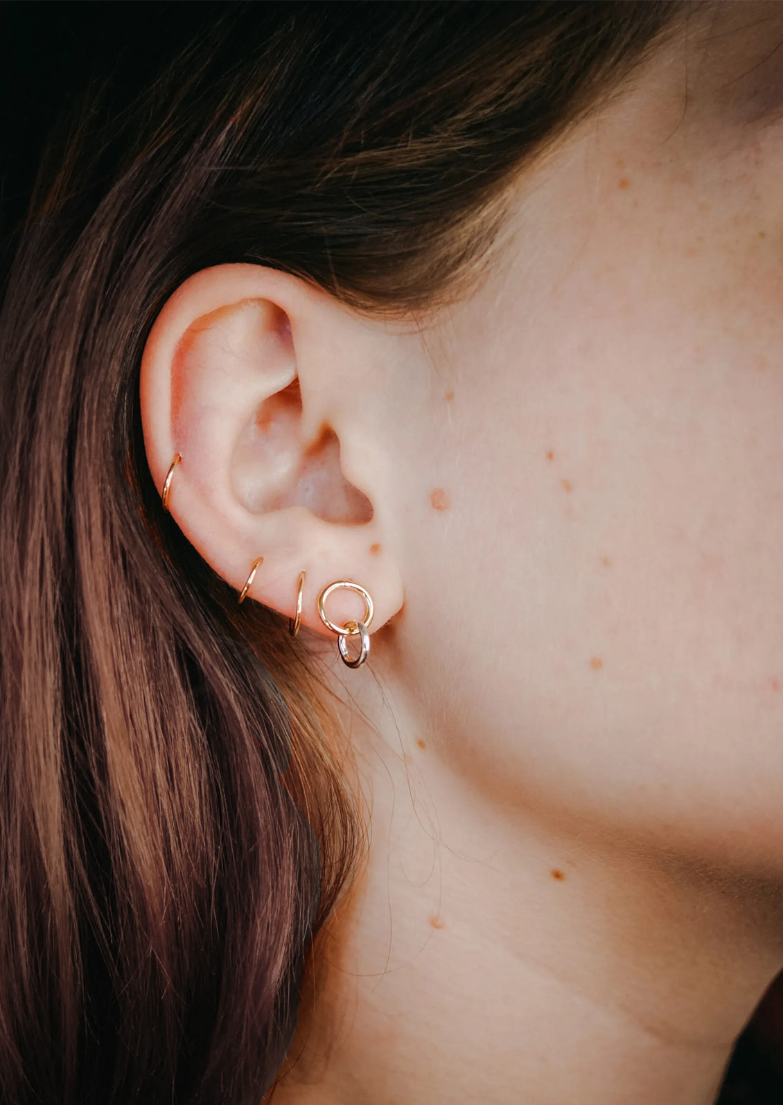 A pair of double circle gold earrings on a model.
