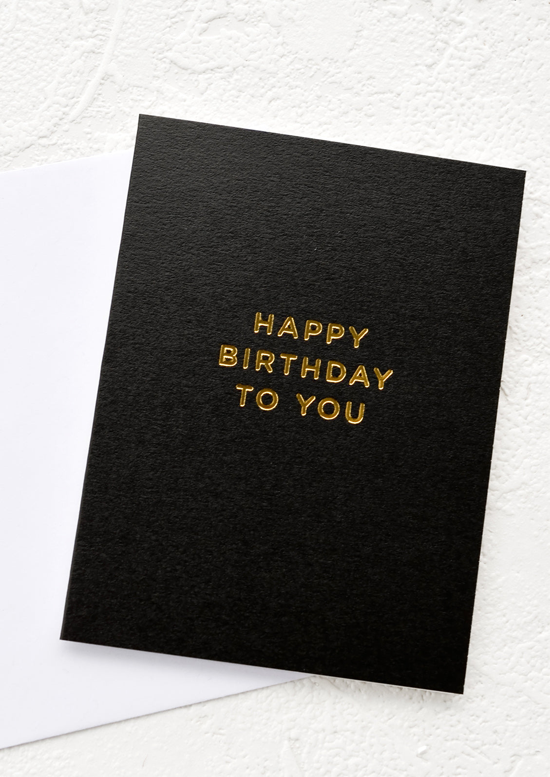 Black greeting card with gold lettering reading "Happy birthday to you"
