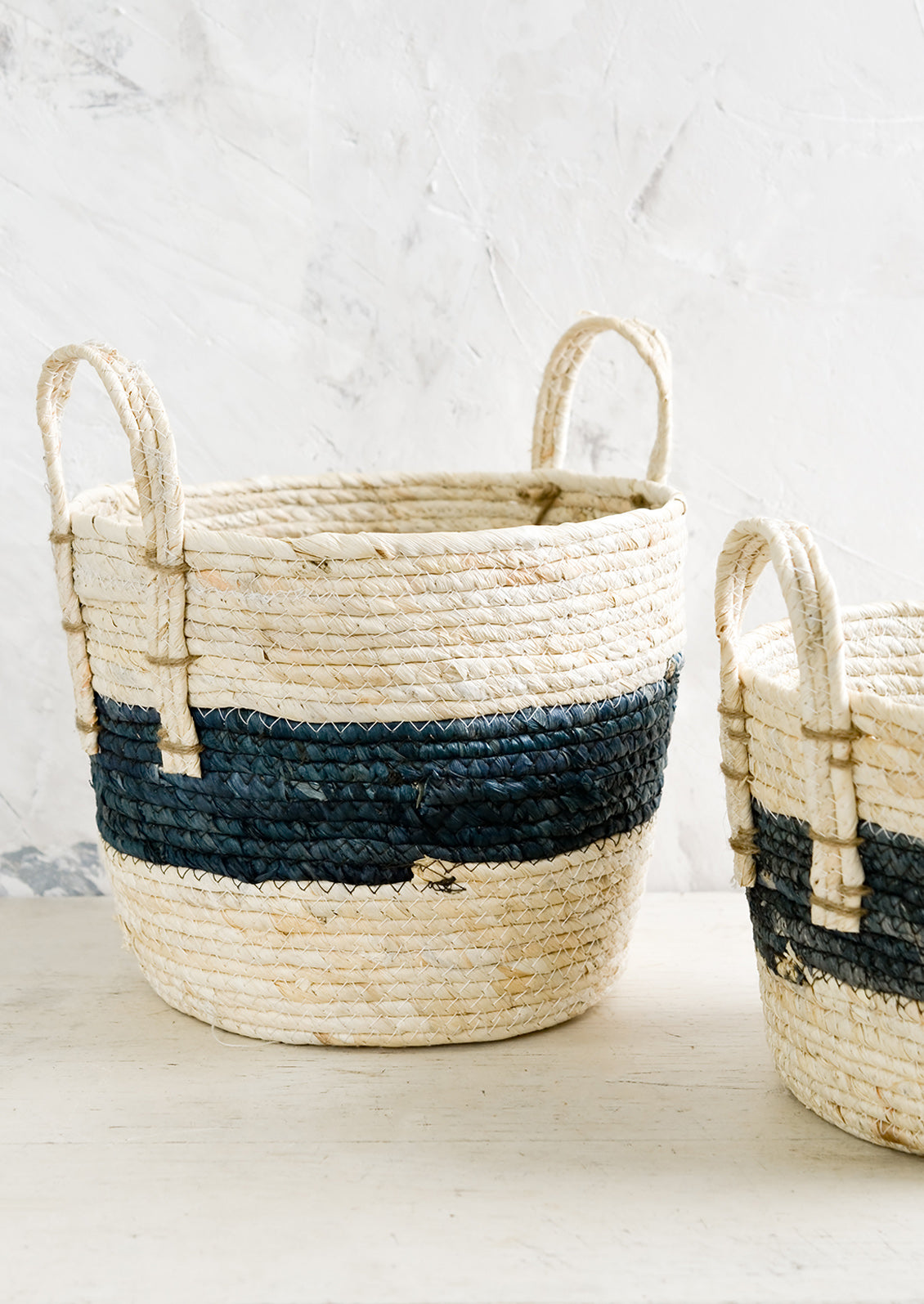 Storage baskets woven from natural maize with indigo band around center.